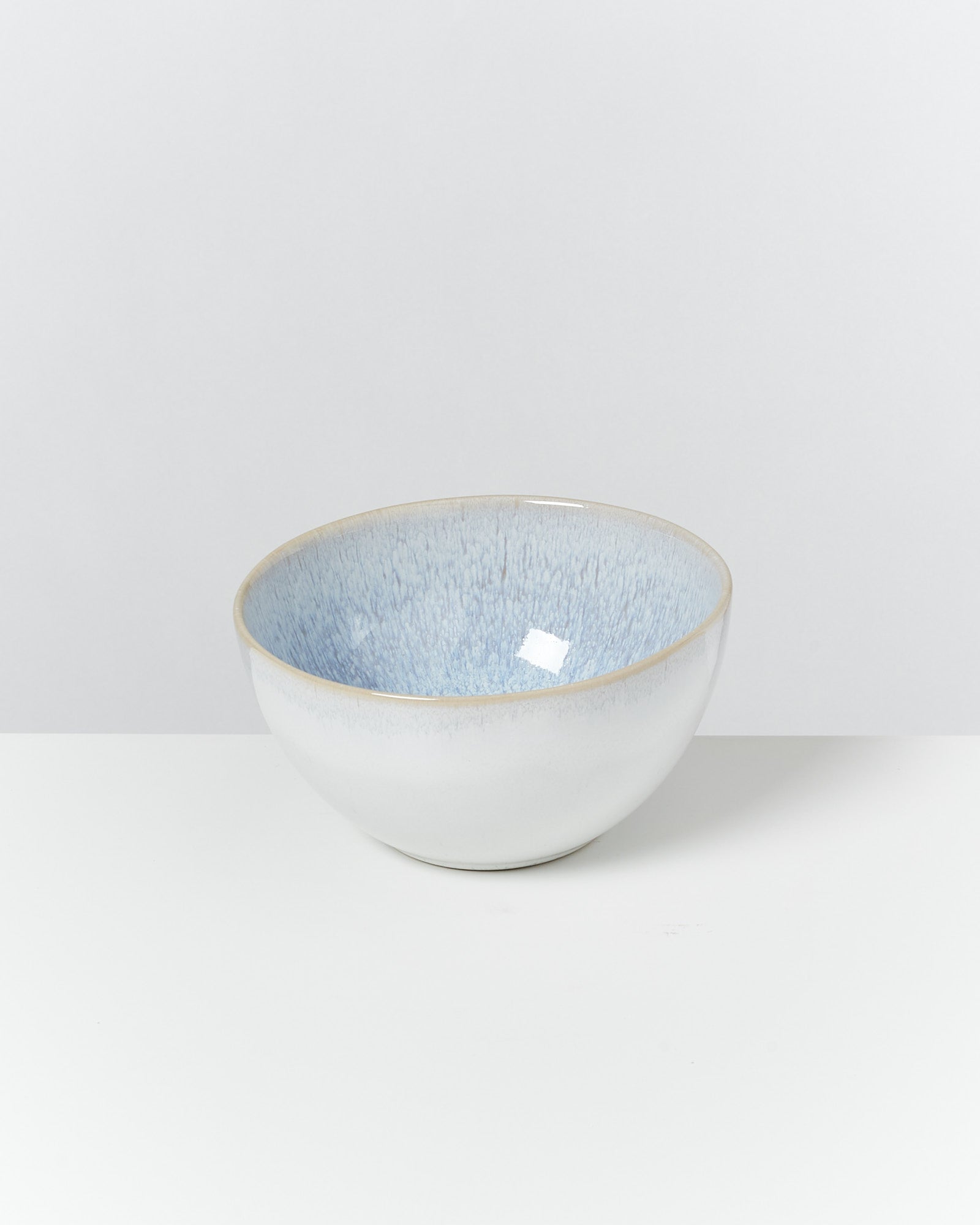 Weiße Schale mit hellblauer Innenseite vor hellem Hintergrund.