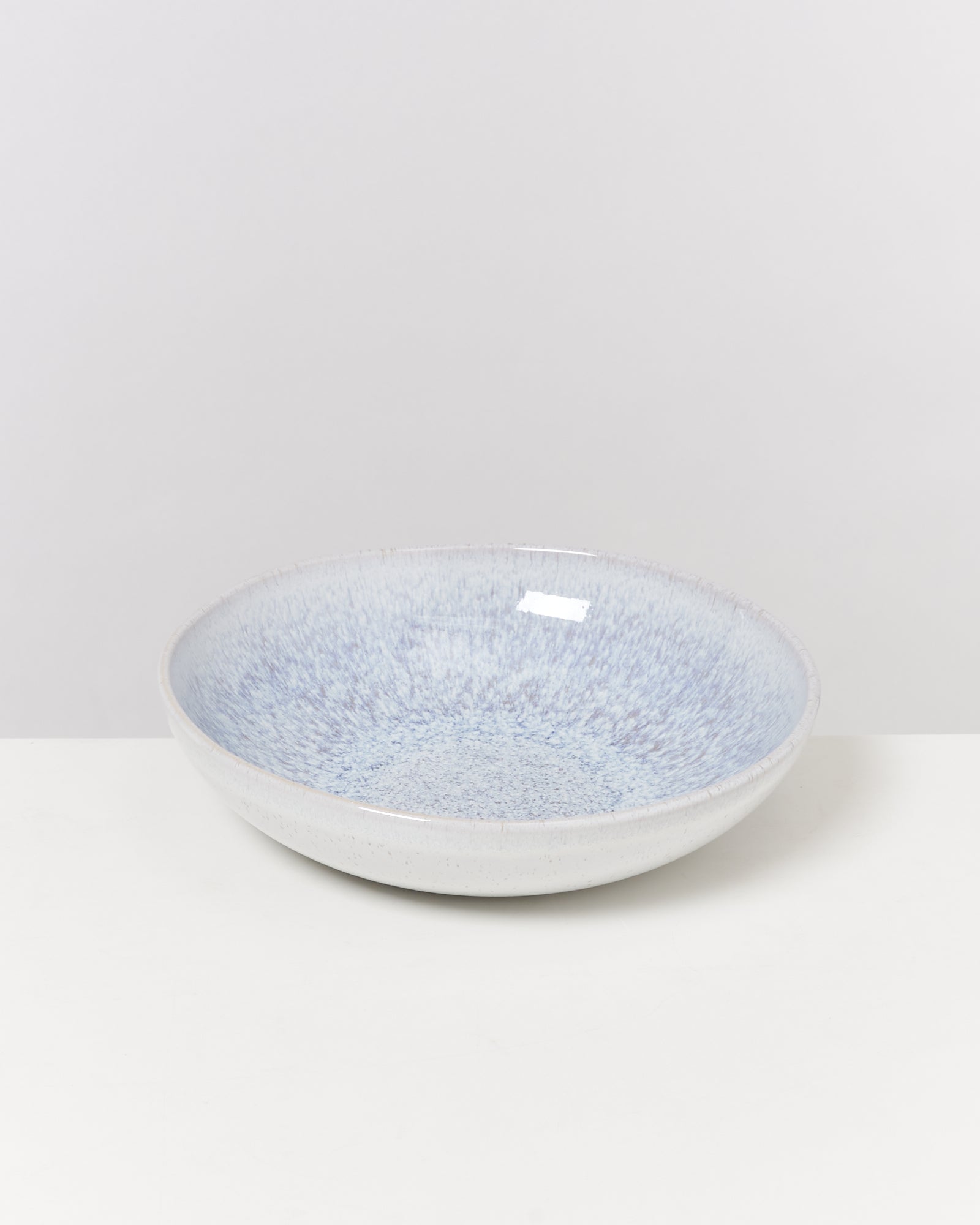 Grauer, flacher Teller mit bläulichem Muster auf einem weißen Hintergrund.