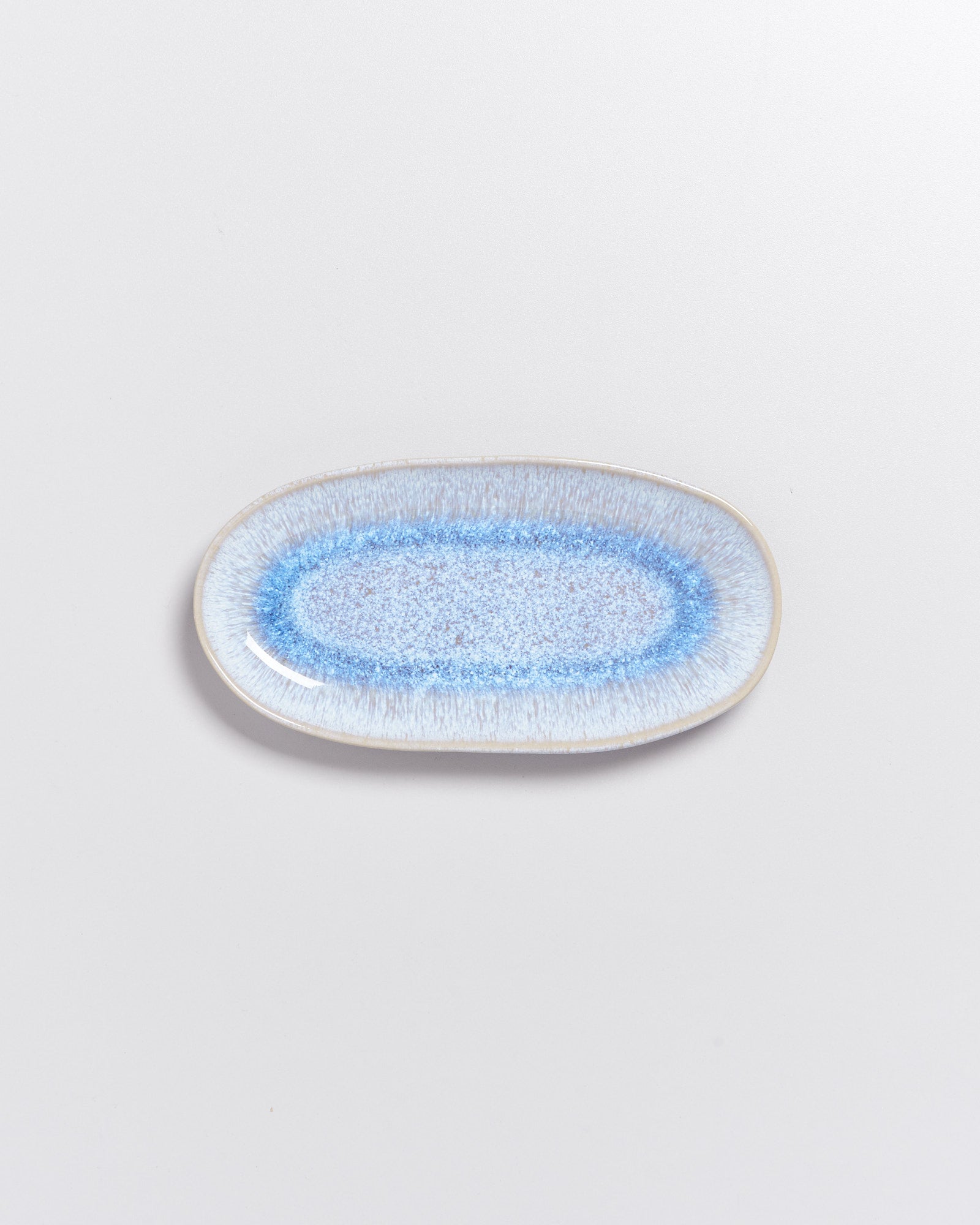 Ovaler Keramikteller mit blauem, gesprenkeltem Muster auf weißem Hintergrund.