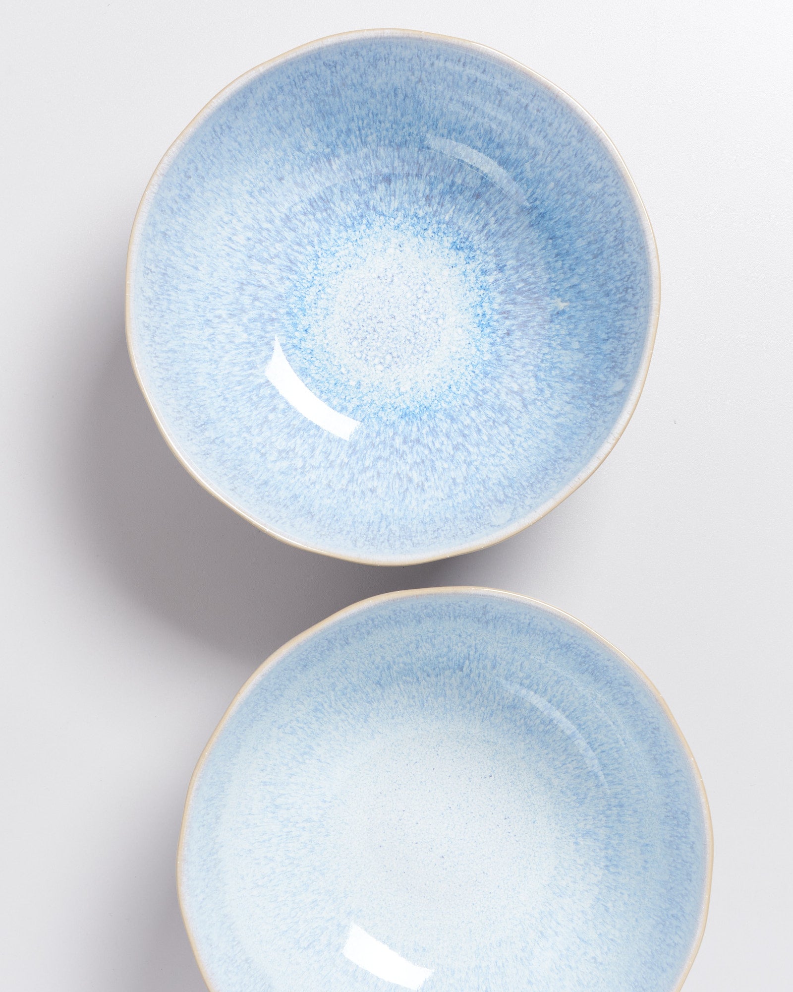 Zwei blaue Keramikschalen mit einem gesprenkelten Muster auf einer weißen Oberfläche.