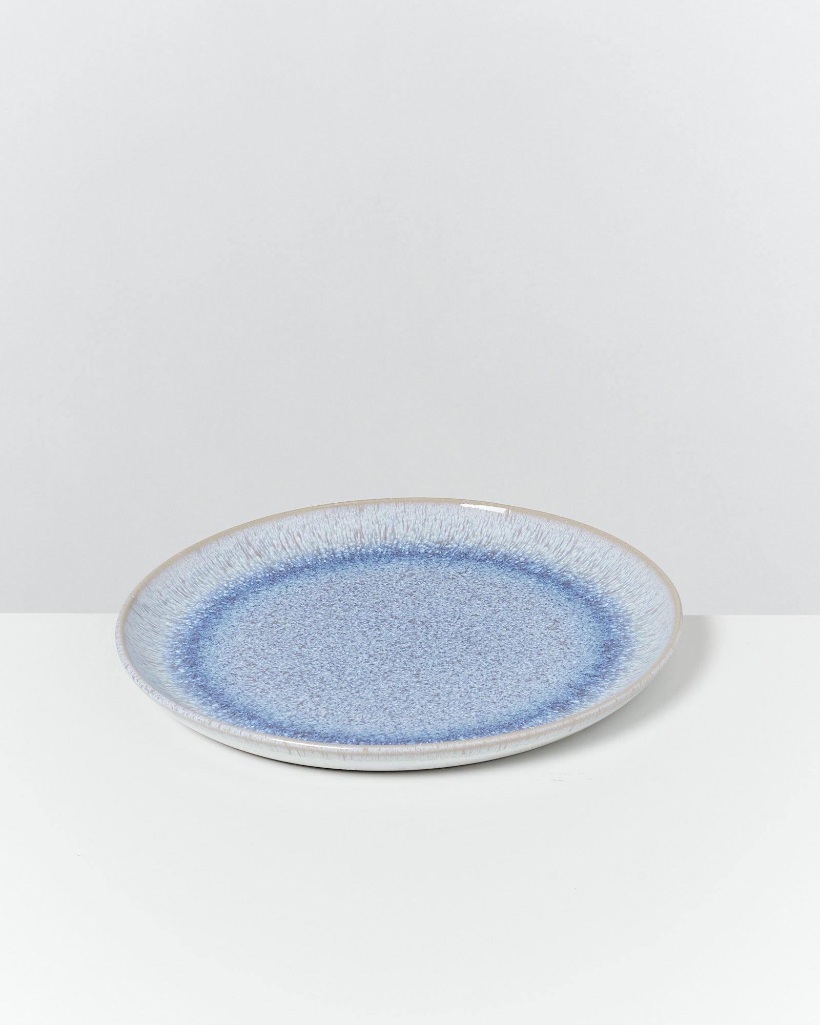 Blauer Keramikteller auf einer weißen Oberfläche vor neutralem Hintergrund.