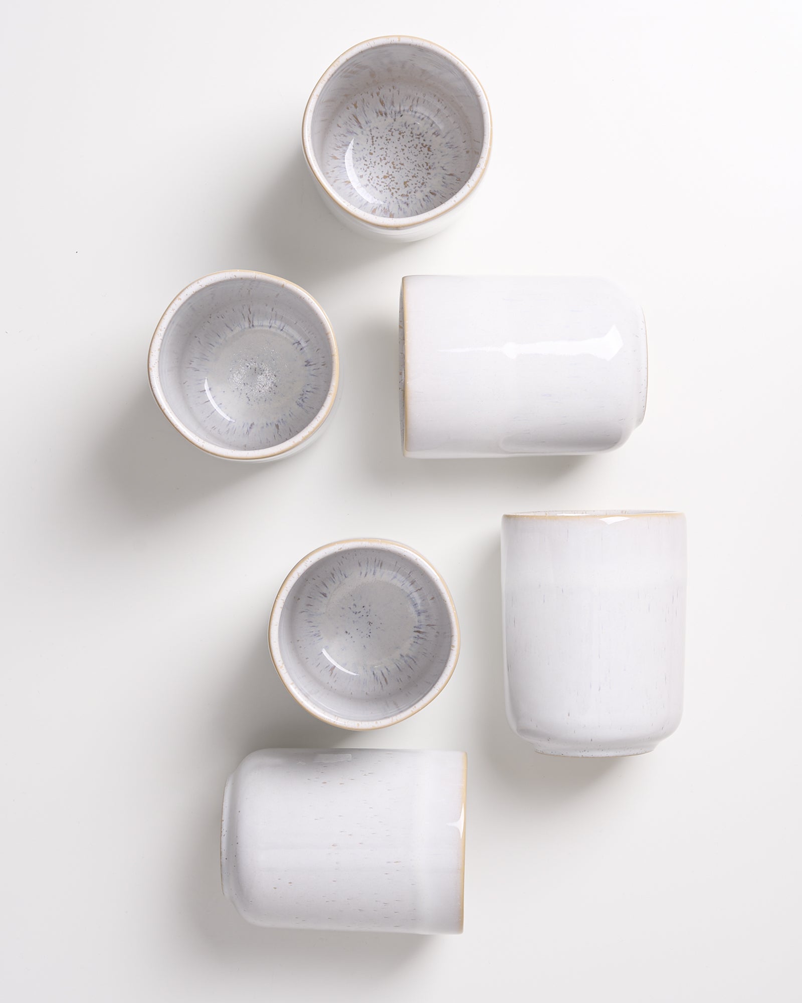Sechs weiße Keramikschüsseln und -becher in verschiedenen Anordnungen auf einem weißen Hintergrund.