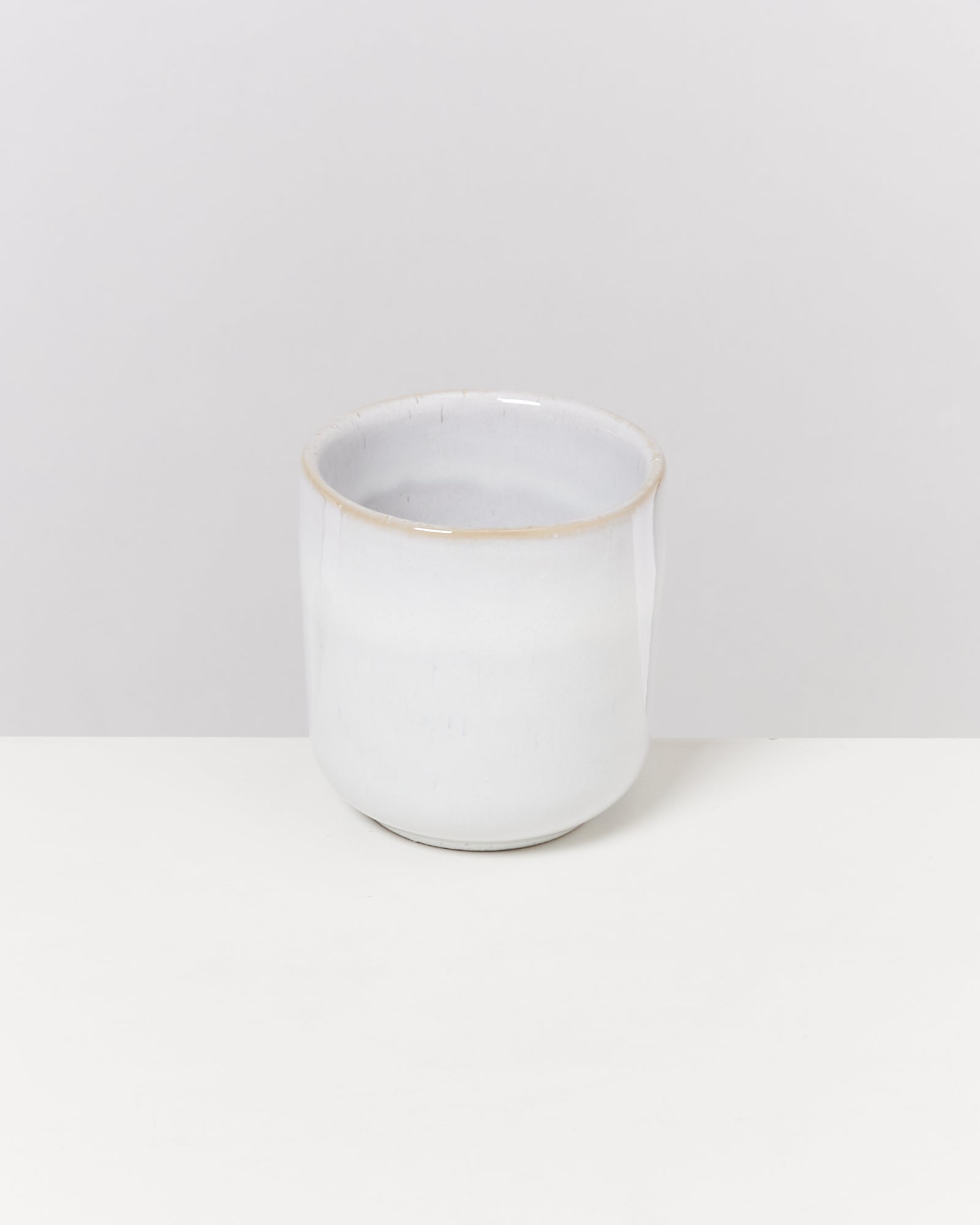 Weiße, glatte Keramiktasse auf einem weißen Hintergrund.