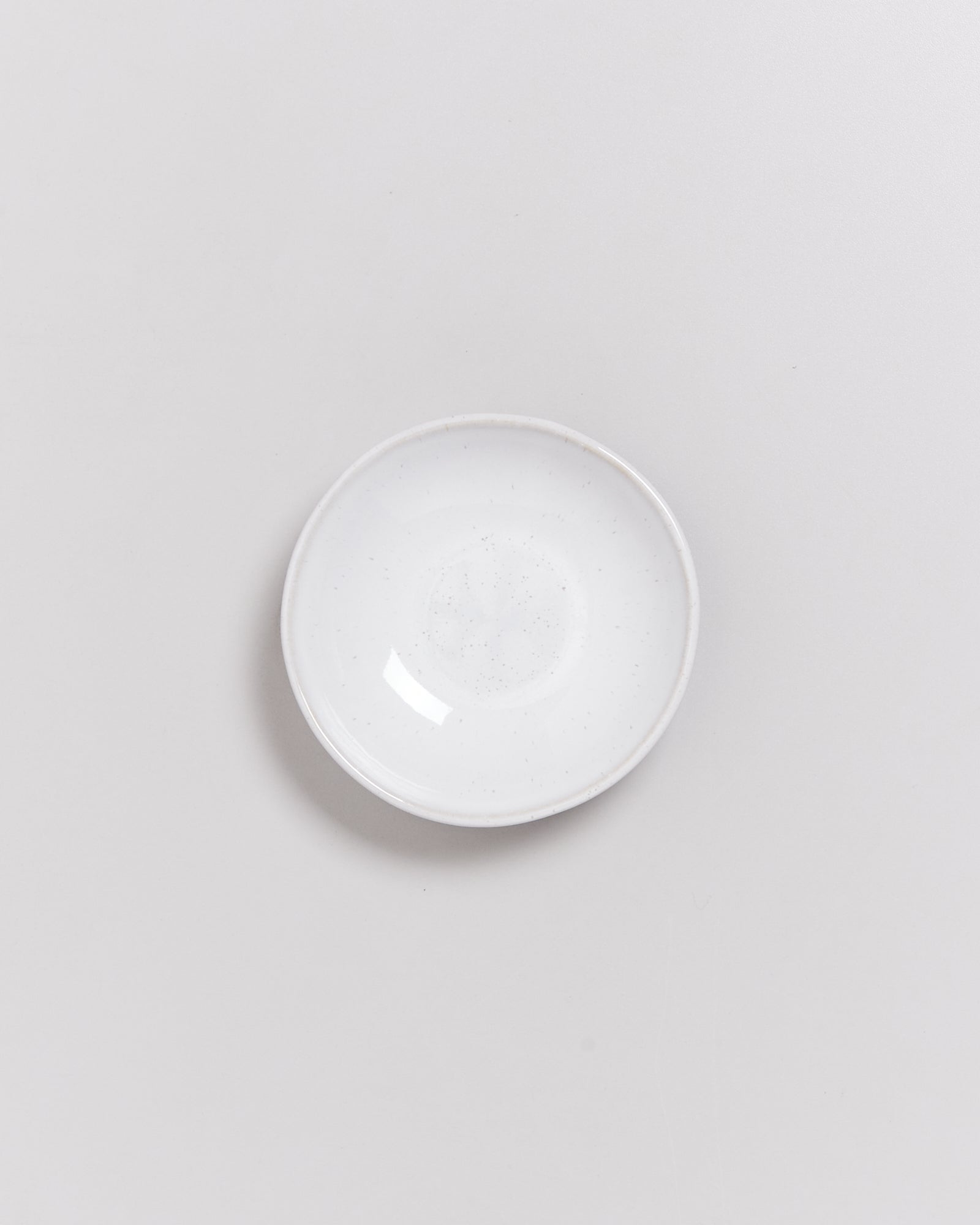 Ein weißer, kreisförmiger Teller auf einem hellgrauen Hintergrund.