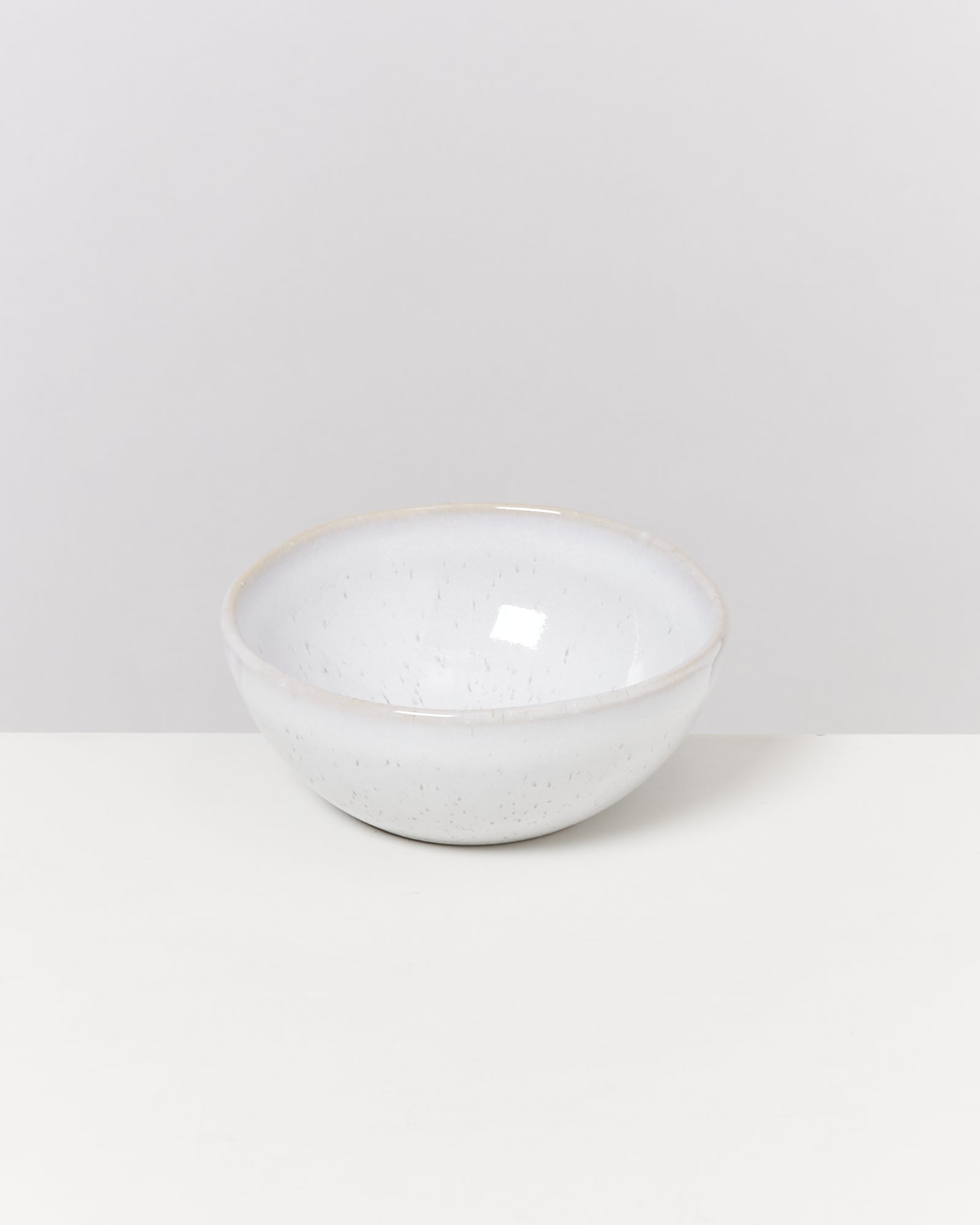 Weiße, keramische Schale mit gesprenkeltem Muster auf einem weißen Hintergrund.