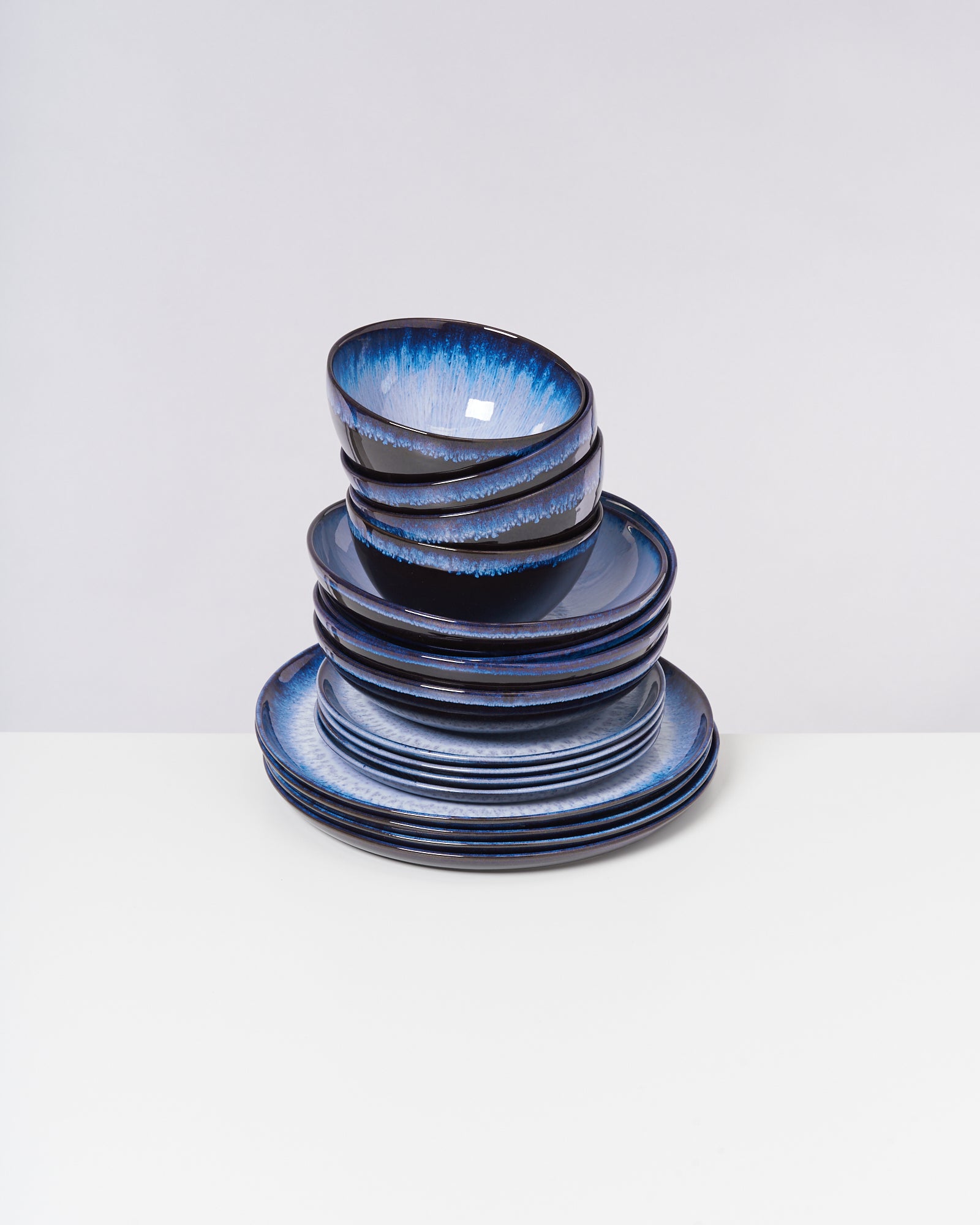 Ein Stapel blauer Keramikschalen und Teller auf einem weißen Hintergrund.