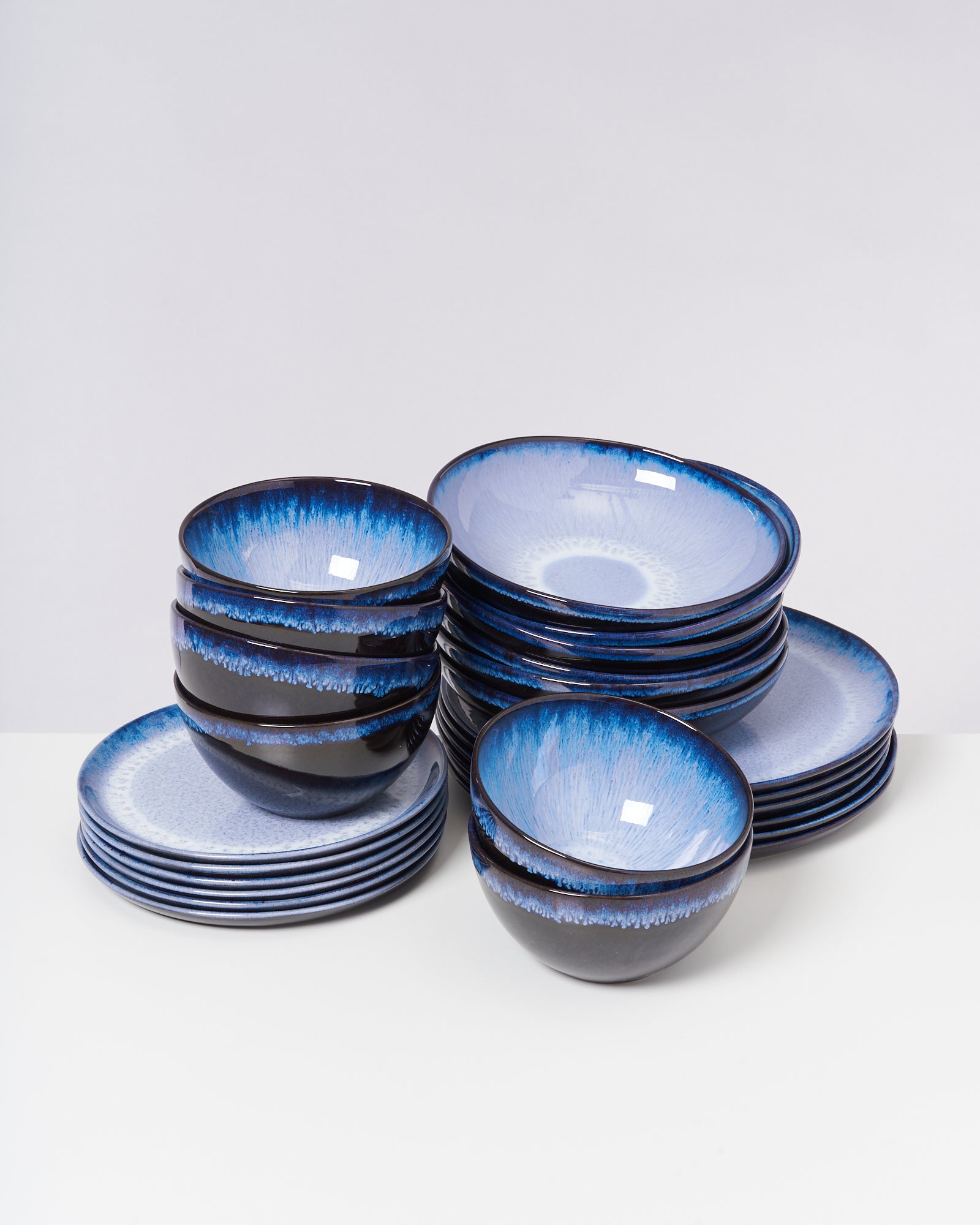 Blau-weiße Keramikschalen und -teller in verschiedenen Stapeln auf weißem Hintergrund.