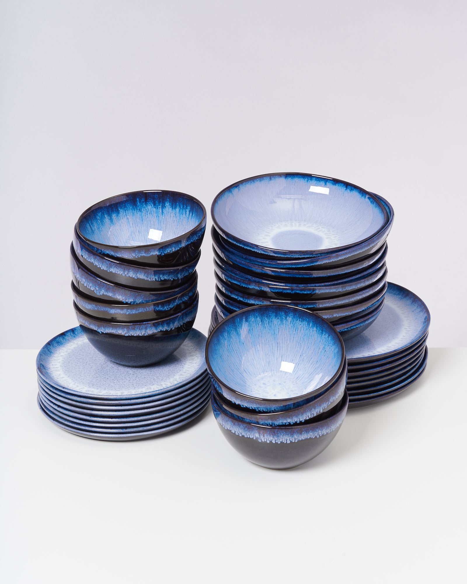 Ein Set aus gestapelten blauen und weißen Schalen und Tellern auf einem weißen Hintergrund.