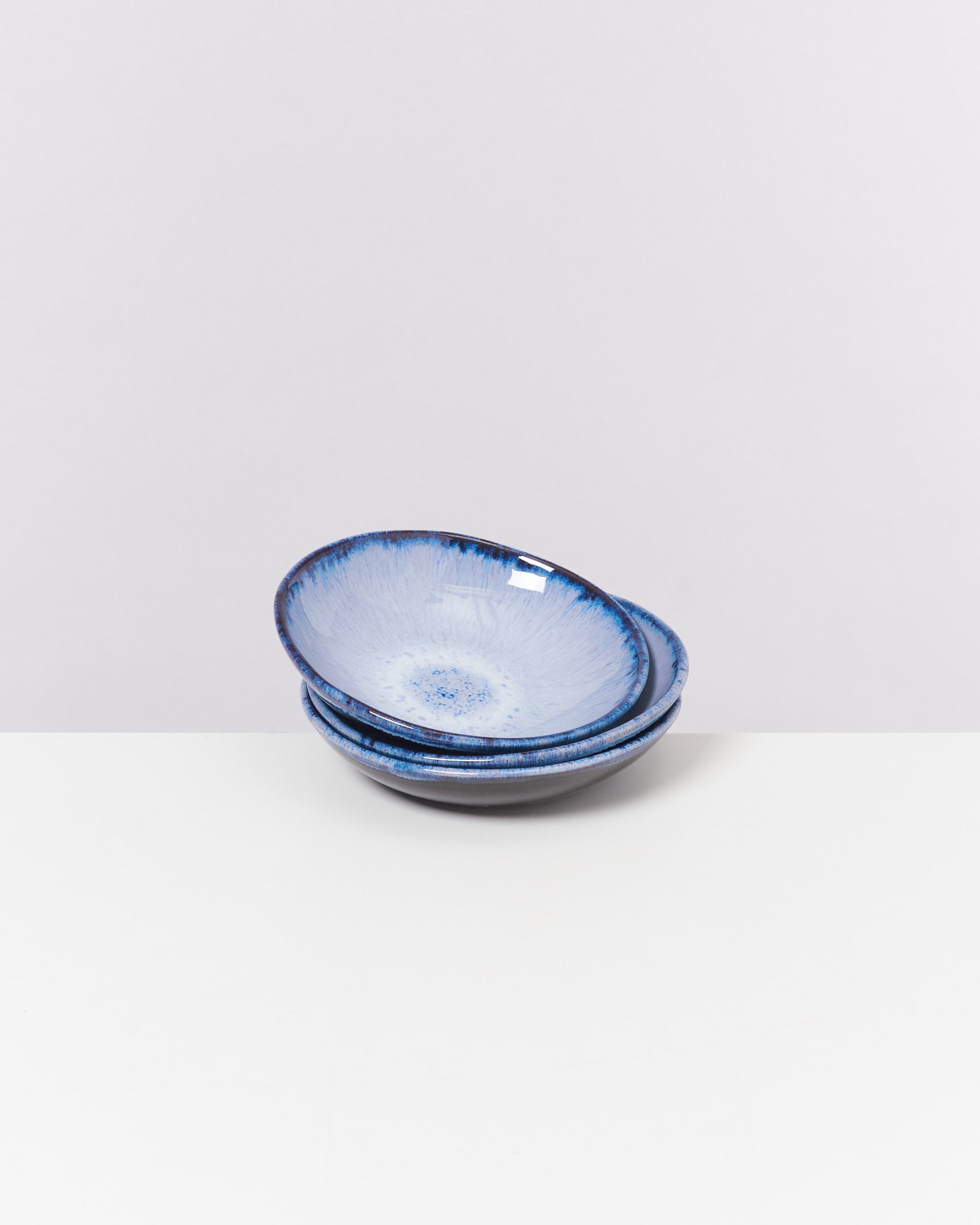 Drei übereinander gestapelte hellblaue Schalen mit dunklem Rand auf weißem Hintergrund.