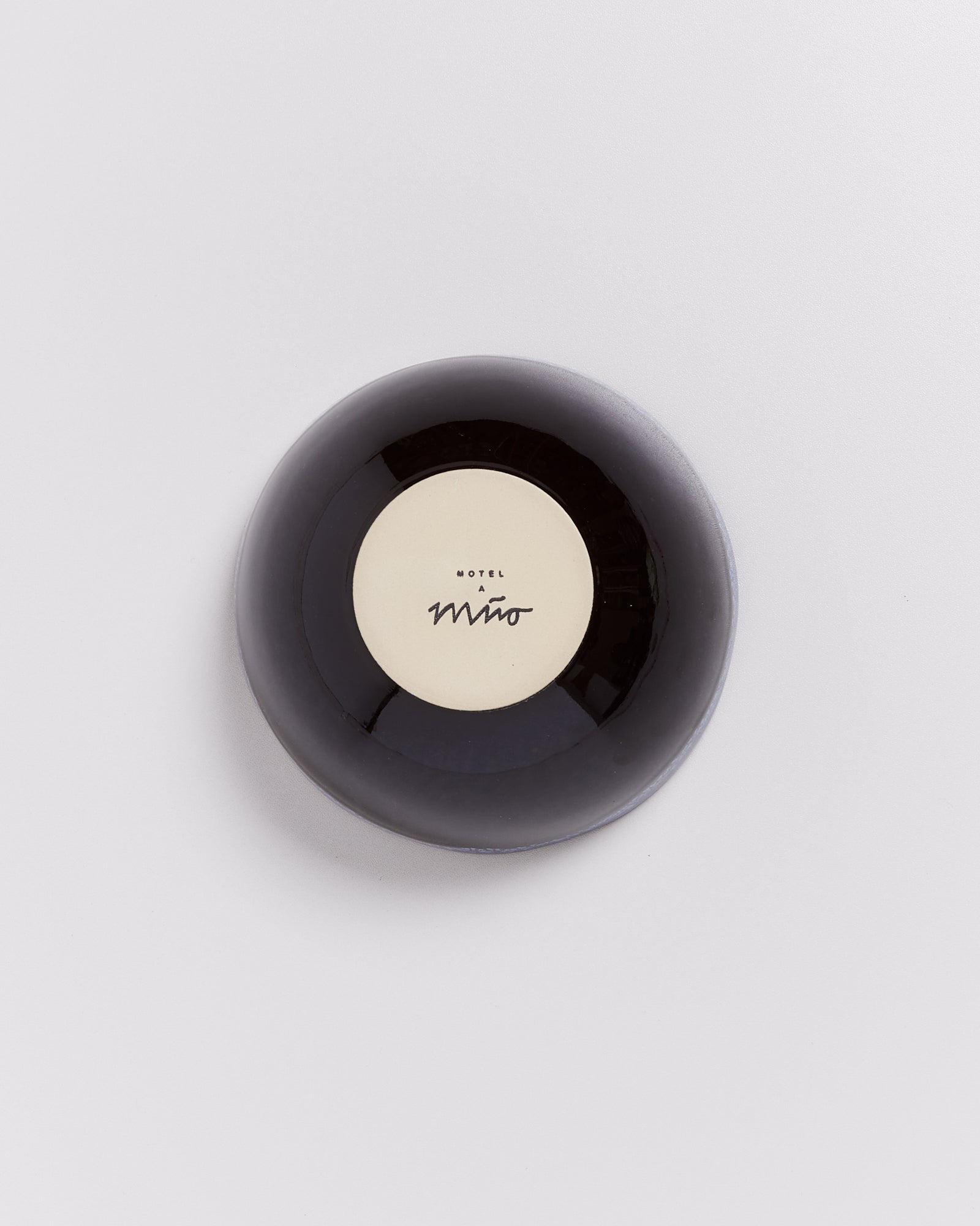 Runde, schwarze Seifenschale mit "Hotel Miro"-Aufschrift auf hellem Hintergrund.