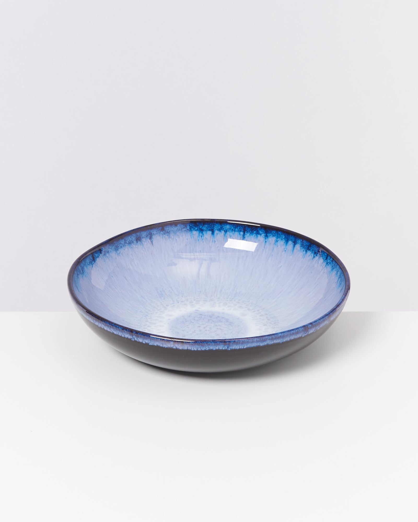 Blau-weiße Keramikschale mit dunklem Rand auf weißem Hintergrund.