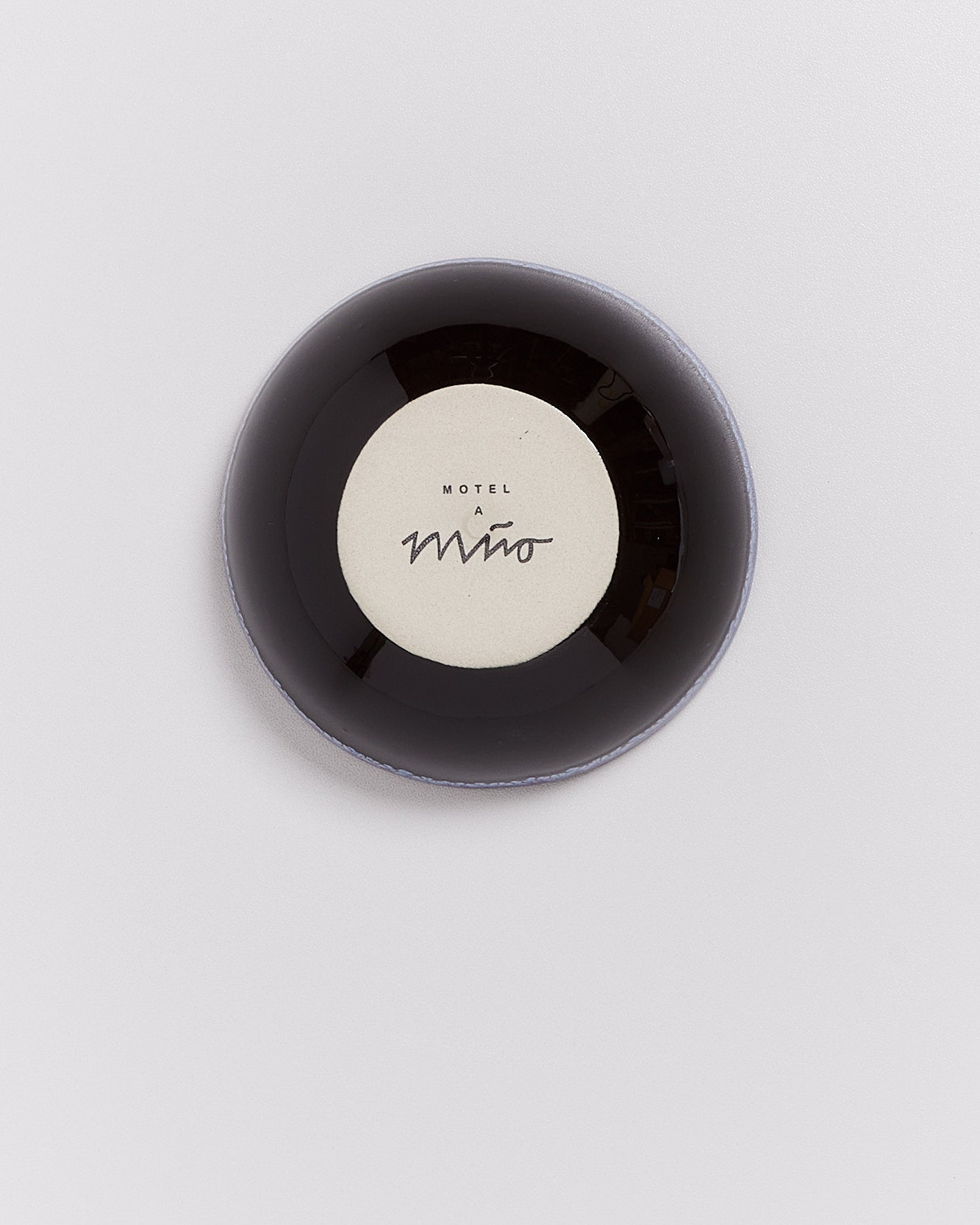Schwarze Schale mit weißem Innenboden, darauf steht "Motel a Miio" in schwarzer Schrift.