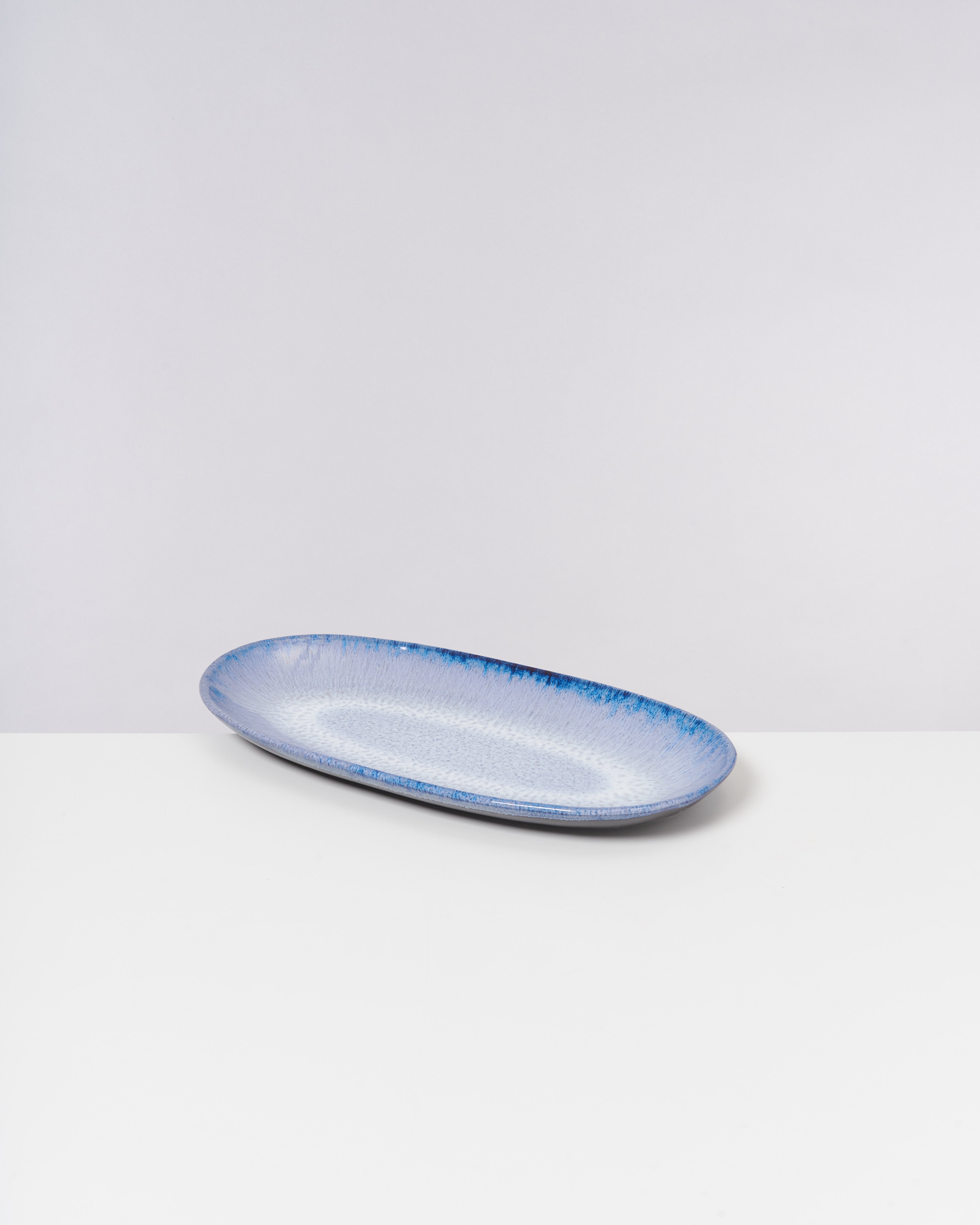 Blauer ovaler Teller auf einem weißen Hintergrund.