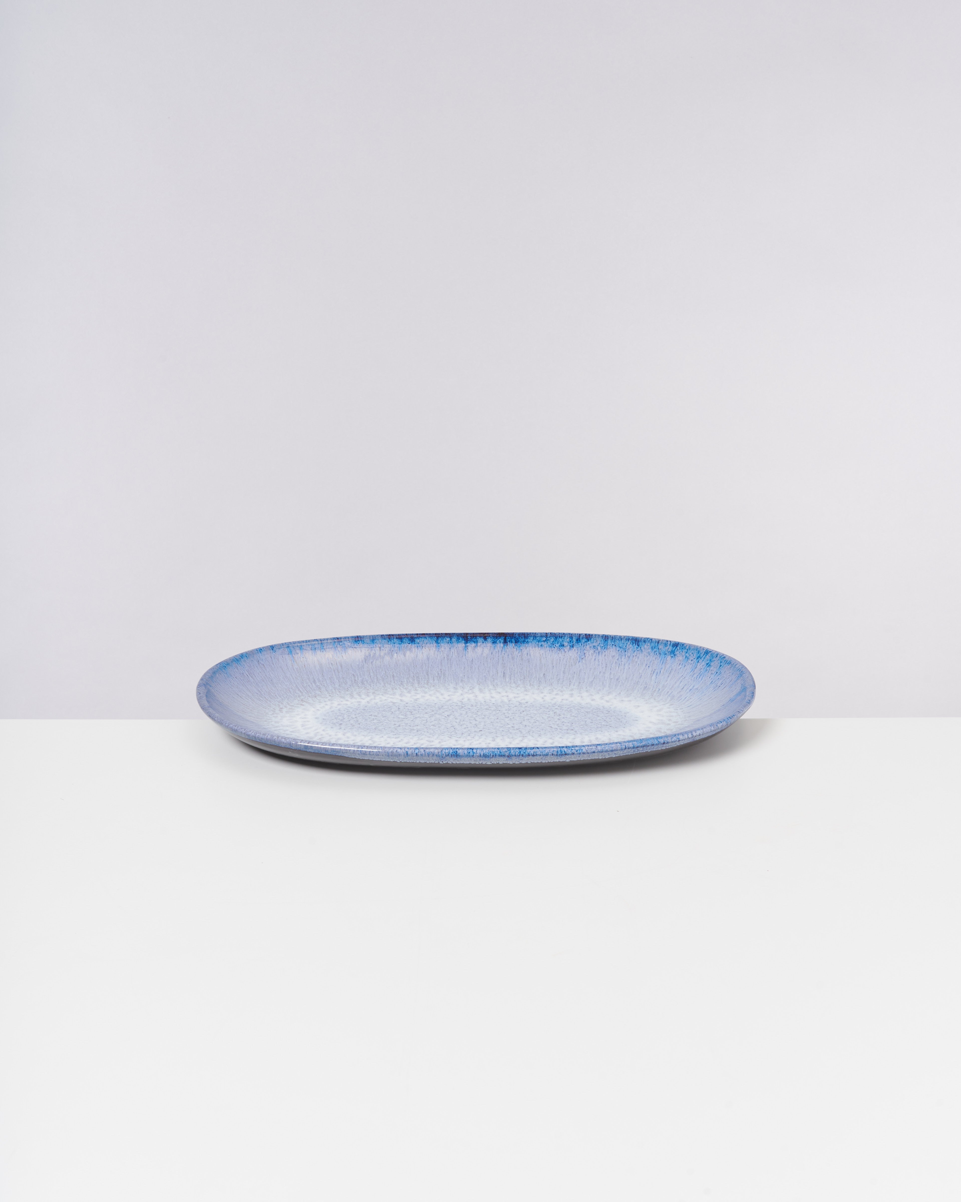 Blauer, ovale Keramikteller auf weißem Hintergrund.