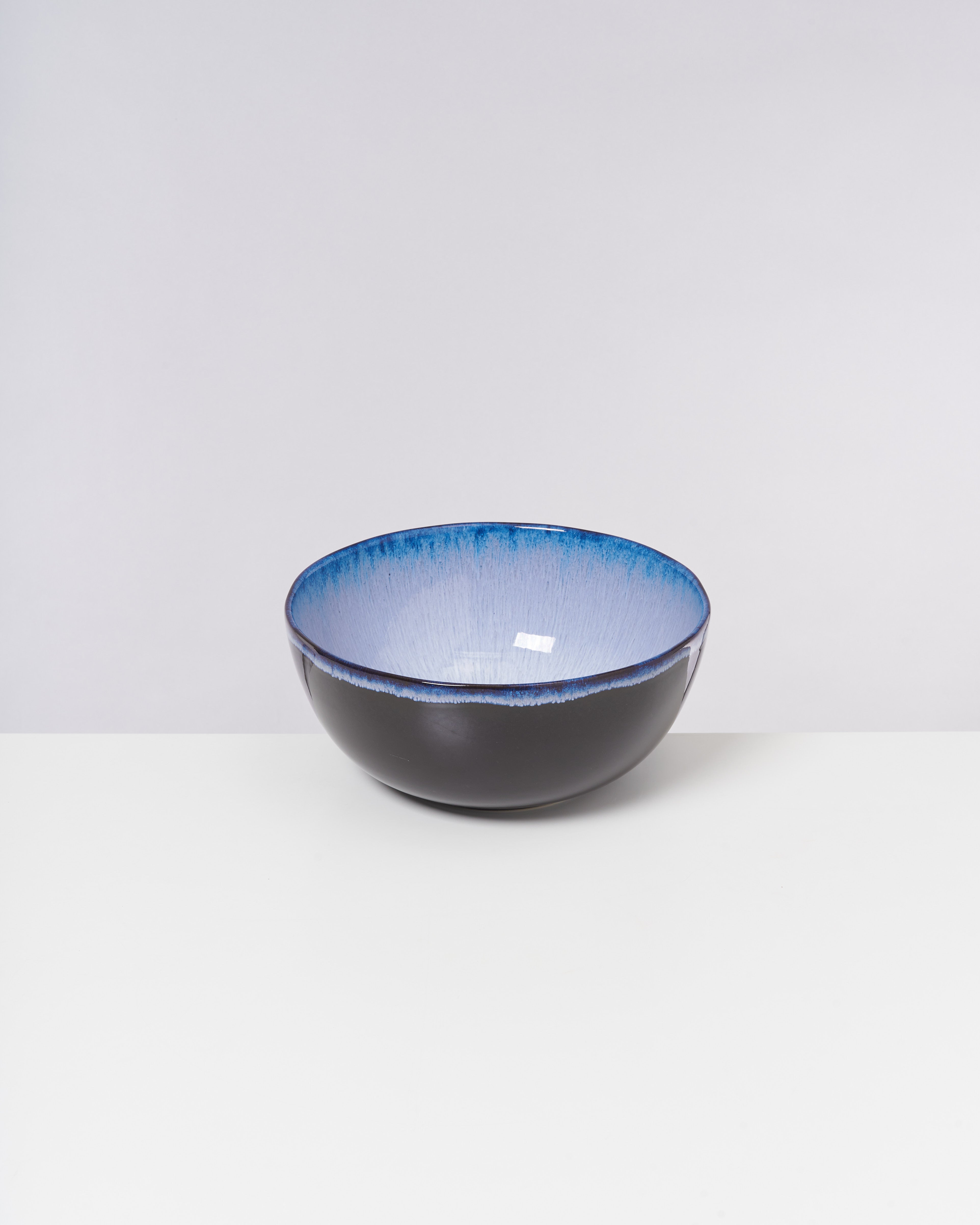 Schwarze Schüssel mit blauem Innenrand steht auf weißem Hintergrund.