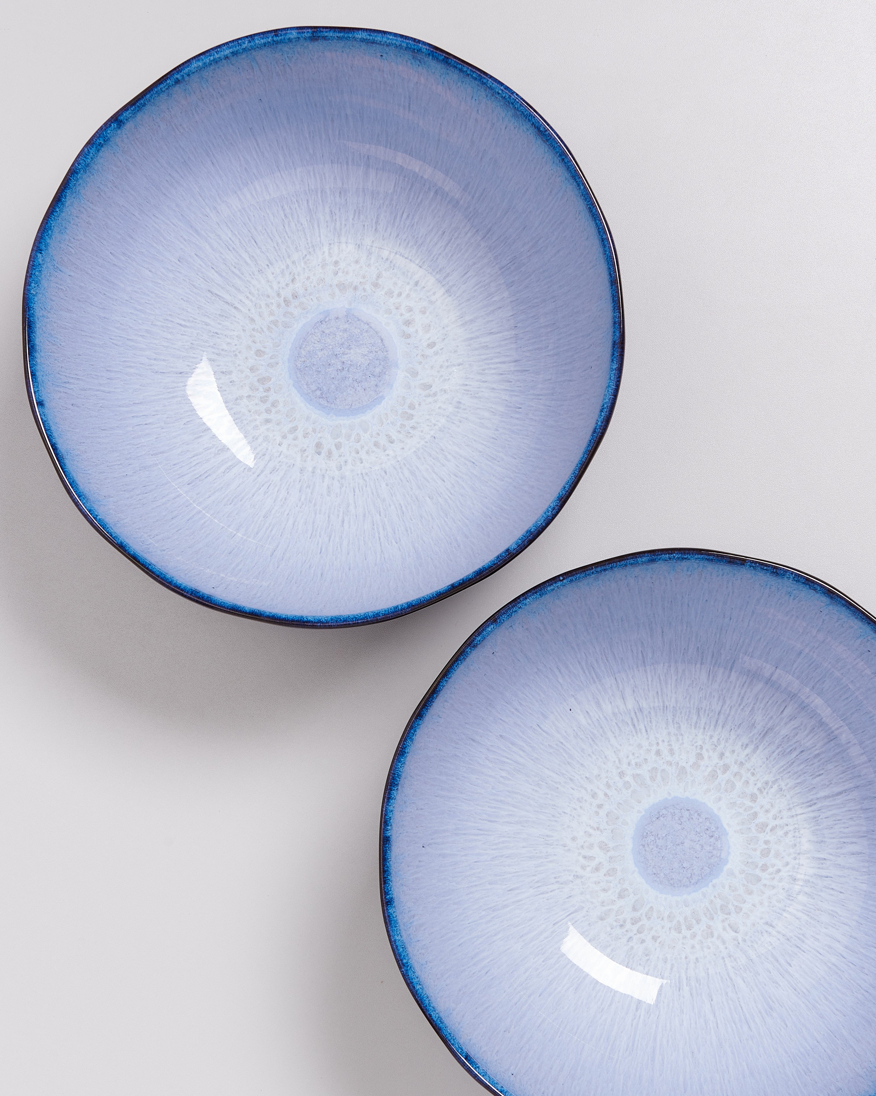 Zwei hellblaue, runde Schalen mit dunkelblauem Rand auf einem hellen Hintergrund.