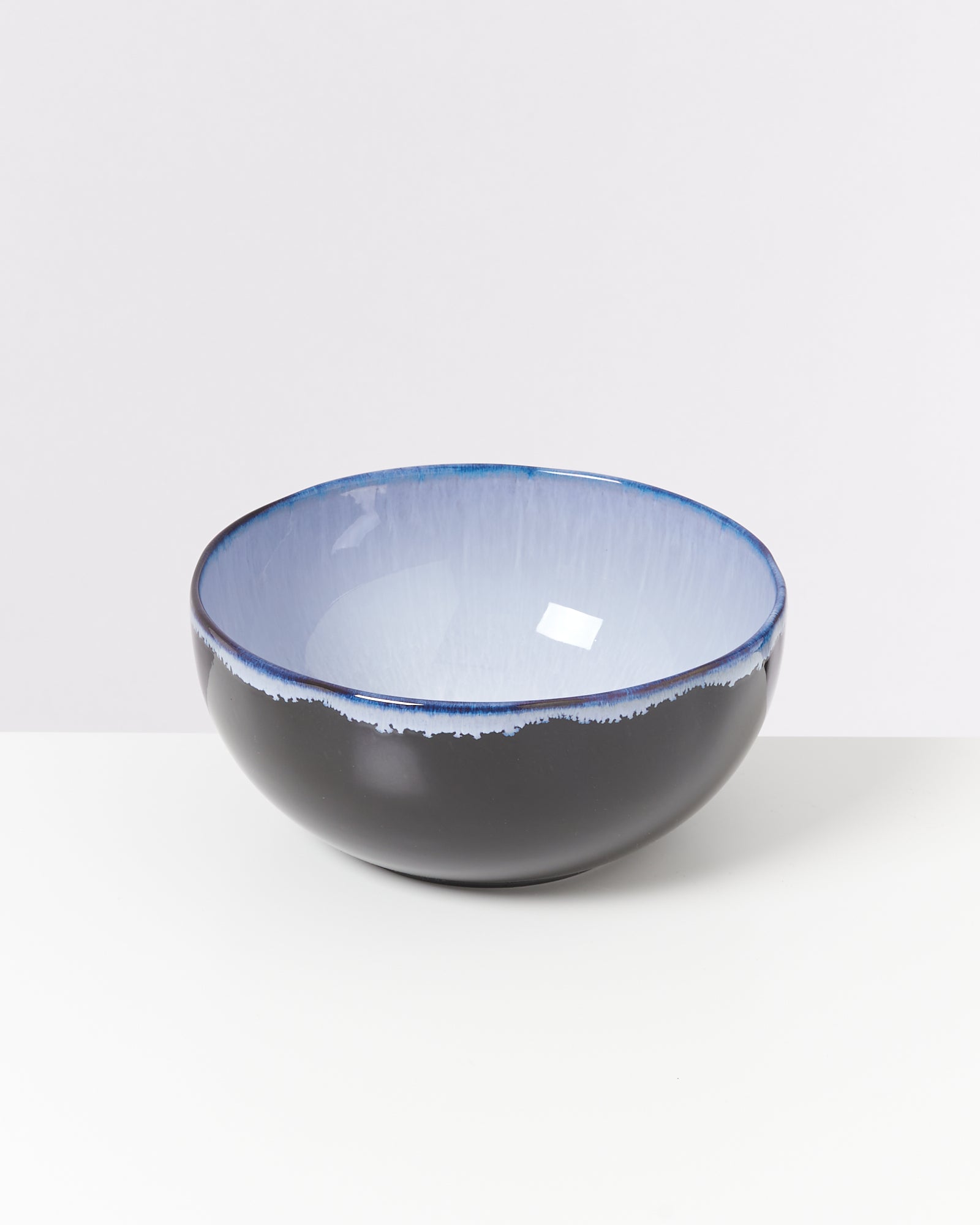 Schwarze Schüssel mit blauem Innenrand steht auf weißem Hintergrund.