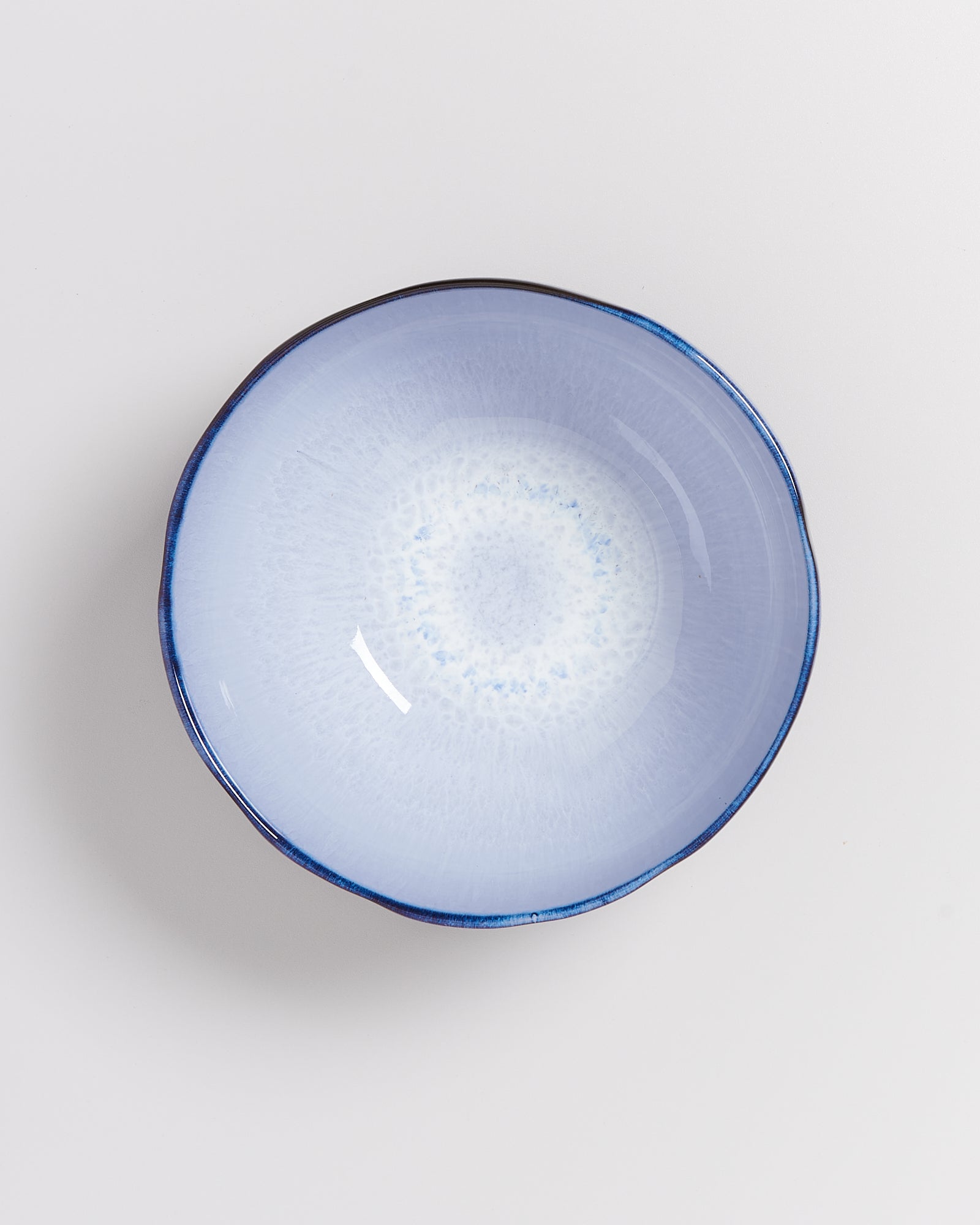 Hellblaue Keramikschale mit dunklem Rand auf weißem Hintergrund.