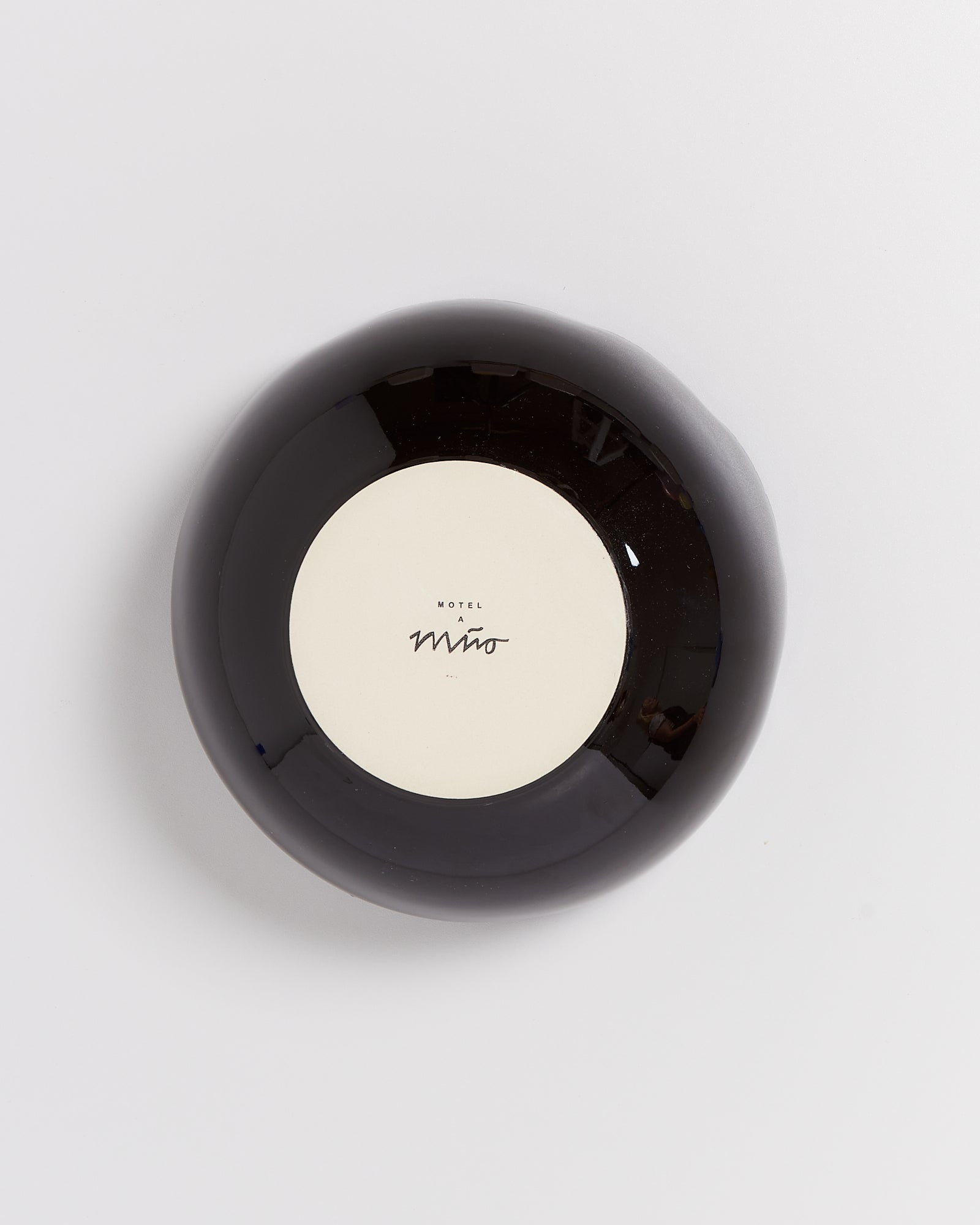 Schwarze Schale mit einem cremefarbenen Boden mit der Aufschrift "Motel Miwo", von oben betrachtet.