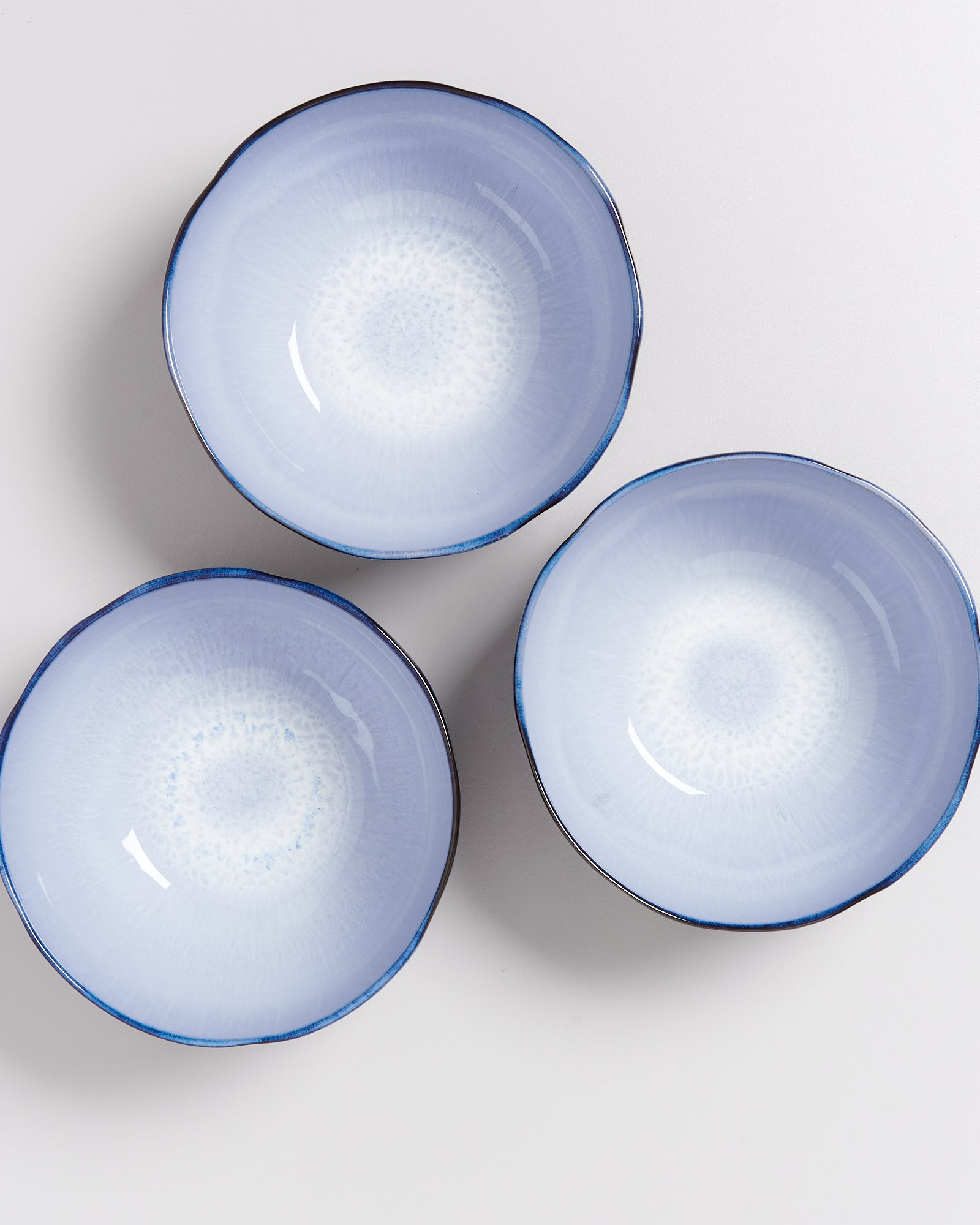 Drei blaue Keramikschalen mit mandalaähnlichen Mustern auf einer weißen Oberfläche arrangiert.