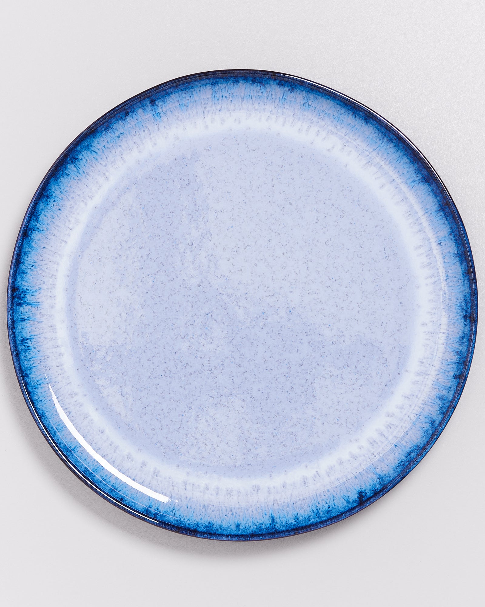Runder Keramikteller mit hellblauer Oberfläche und dunkelblauem Rand auf weißem Hintergrund.