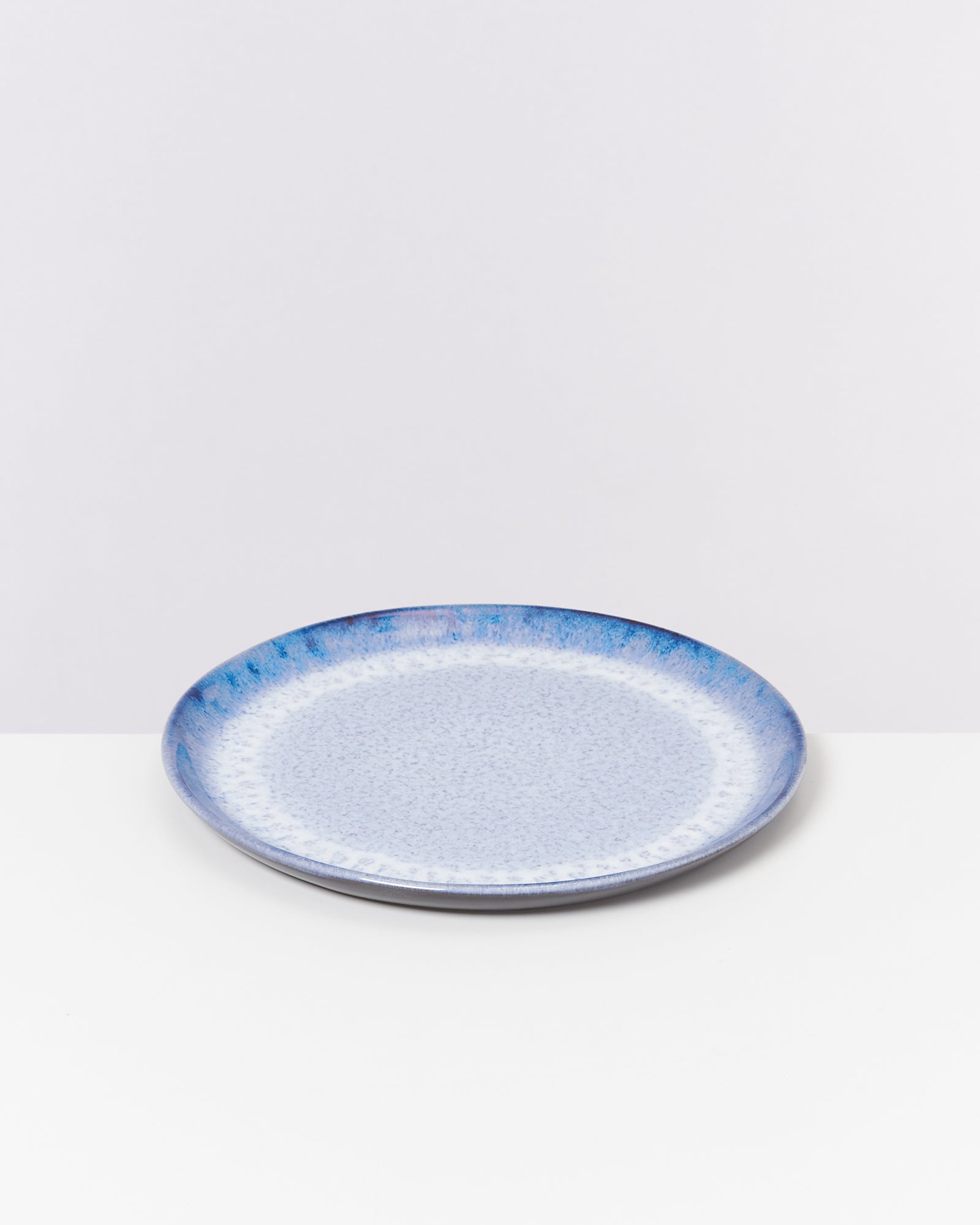 Blauer Teller mit gesprenkeltem Muster auf weißem Hintergrund.