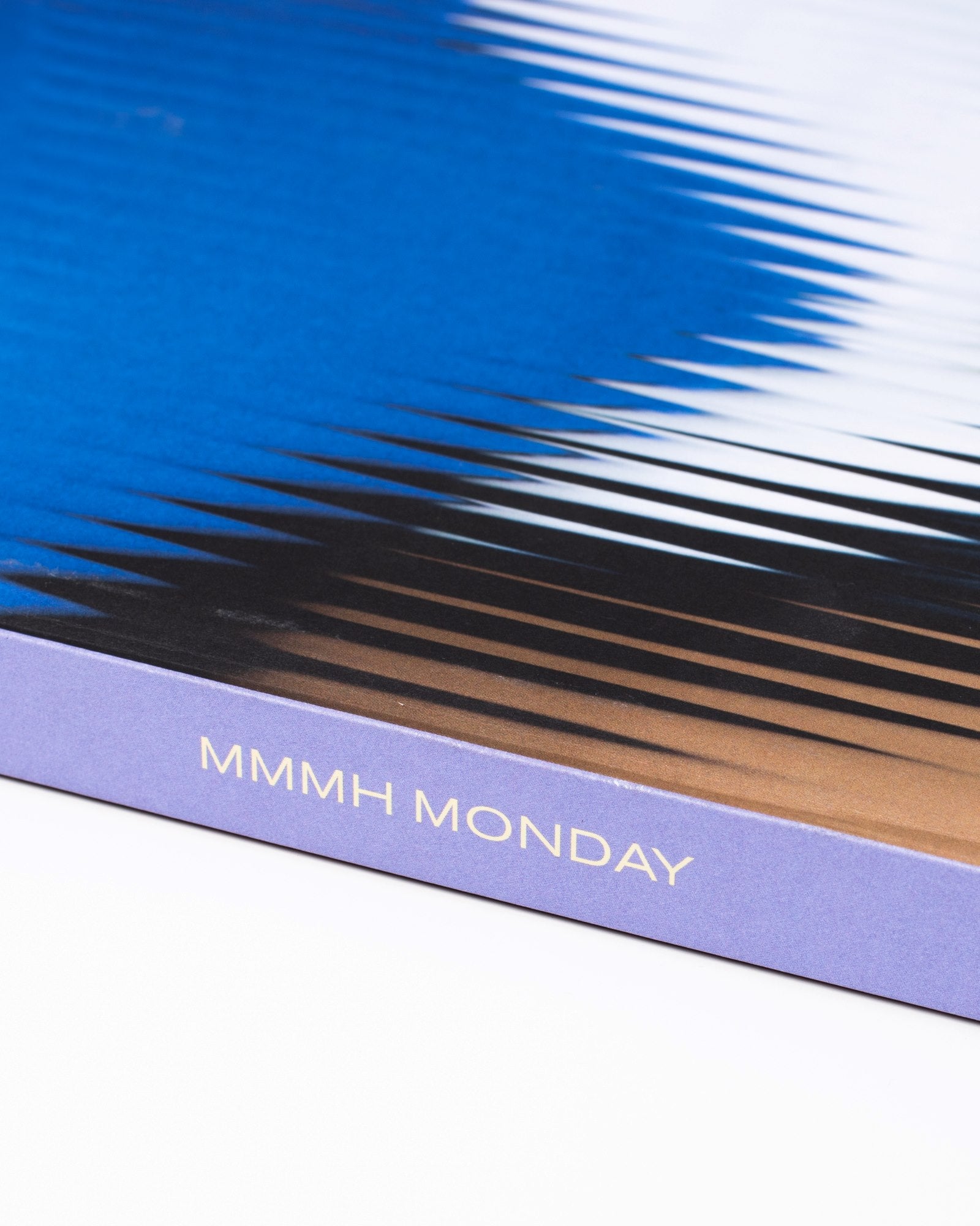 Nahaufnahme eines blauen Buchcovers mit der Aufschrift "MMMH MONDAY" an der Seite.