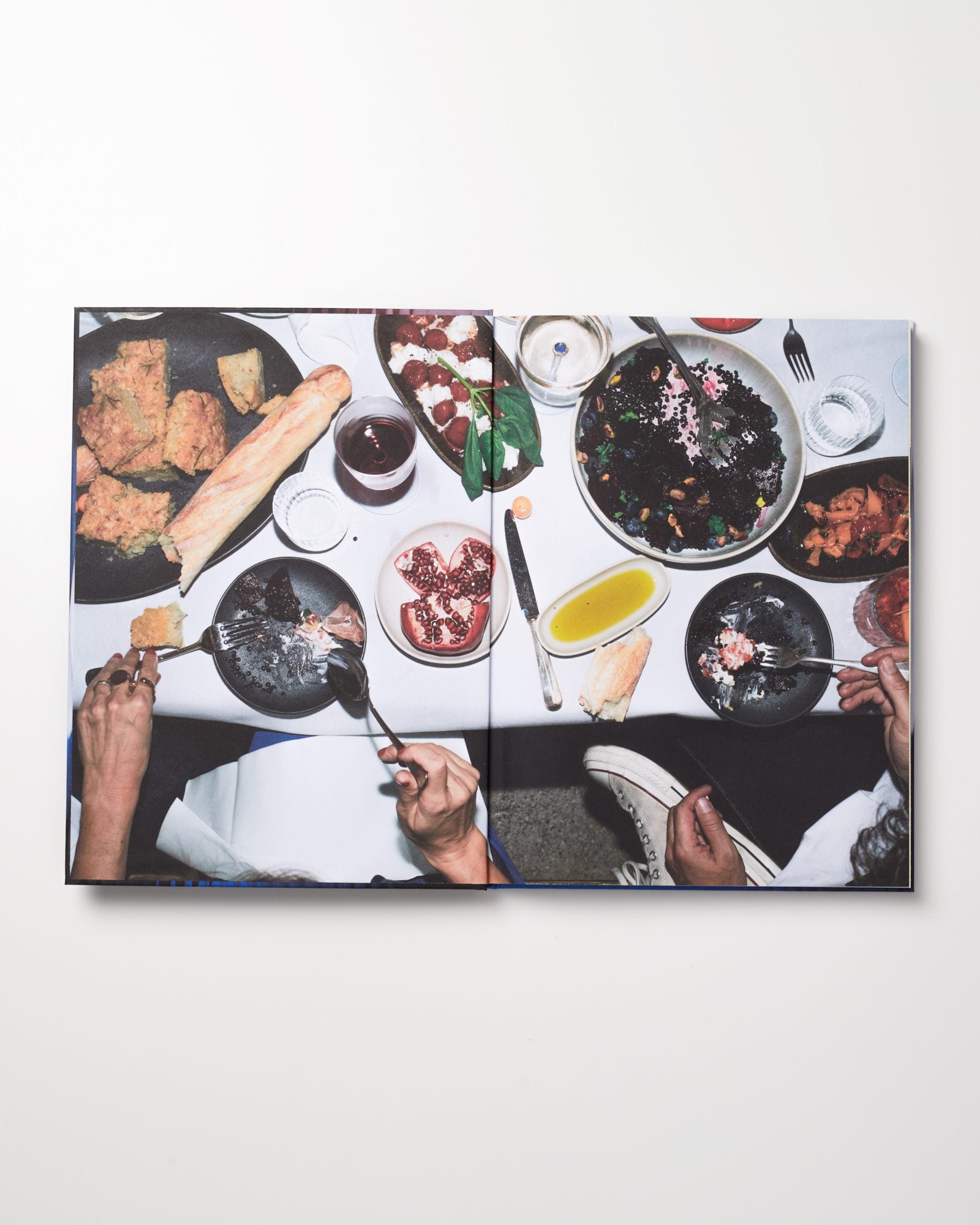 Vogelperspektive auf einen Tisch mit verschiedenen Speisen und Getränken, zwei Personen essen mit Gabeln.