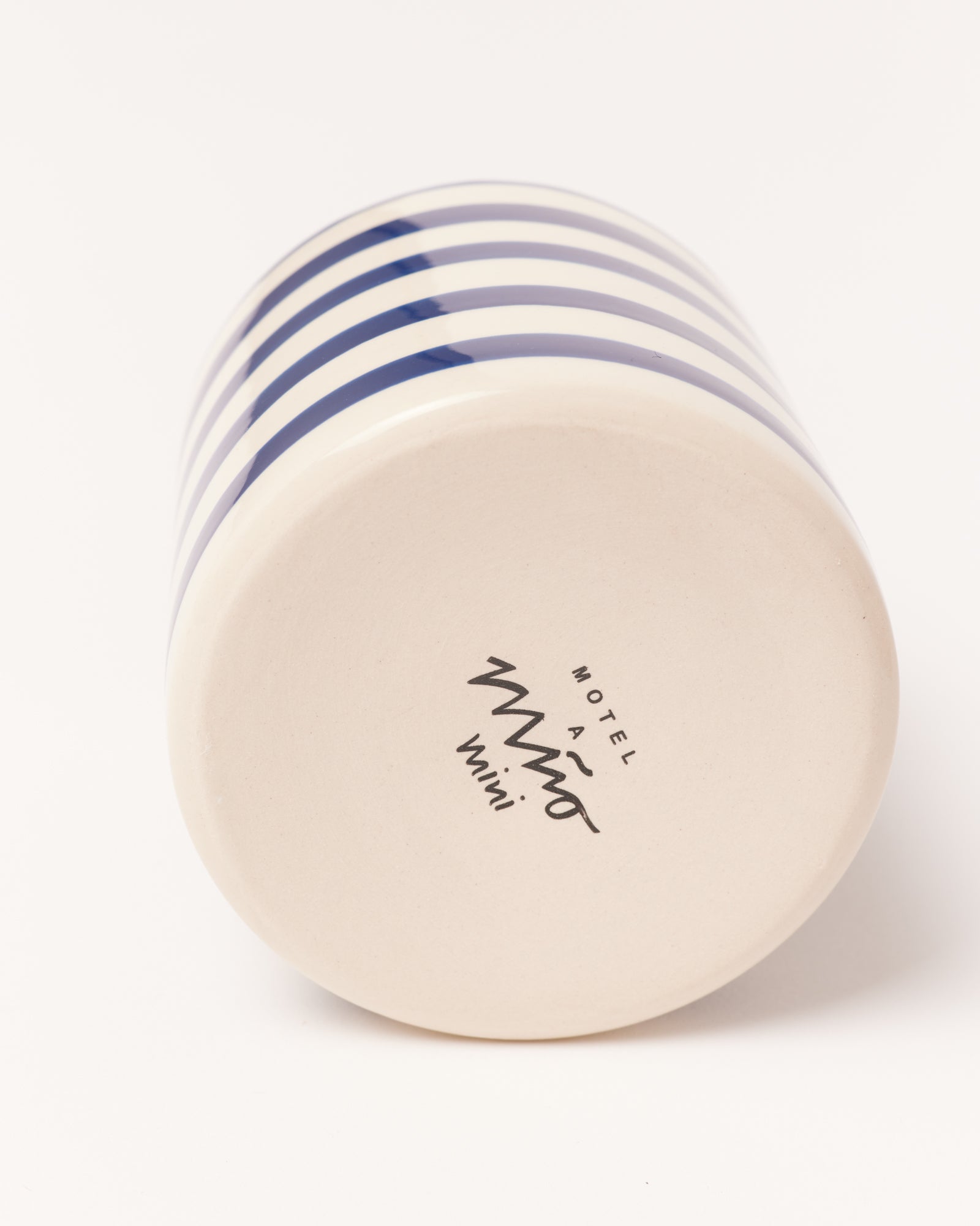 Unterseite eines Bechers mit blauen Streifen und einer Aufschrift, die "Motel a Miio mini" zeigt.