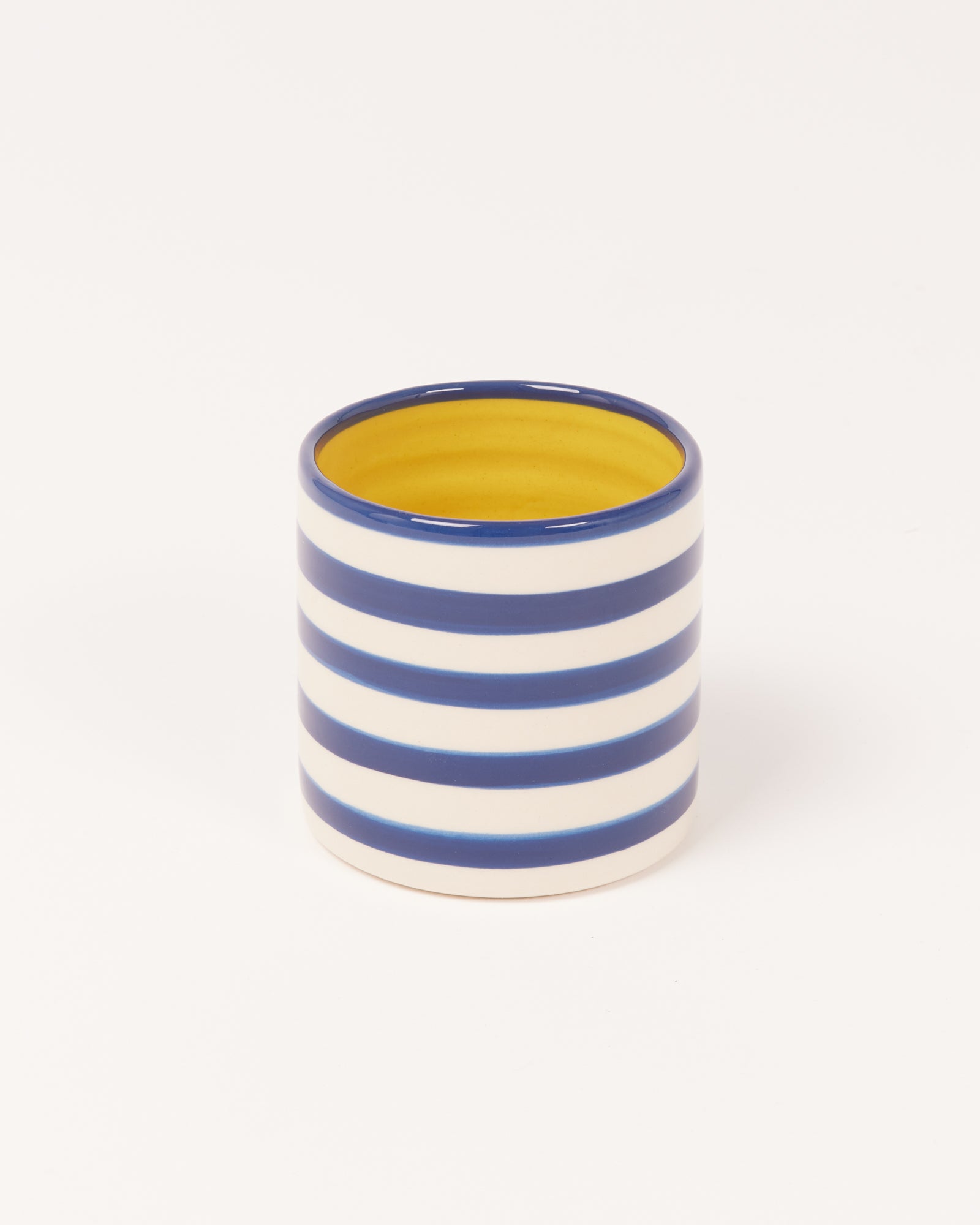 Keramikbecher mit blauen und weißen Streifen, innen gelb.