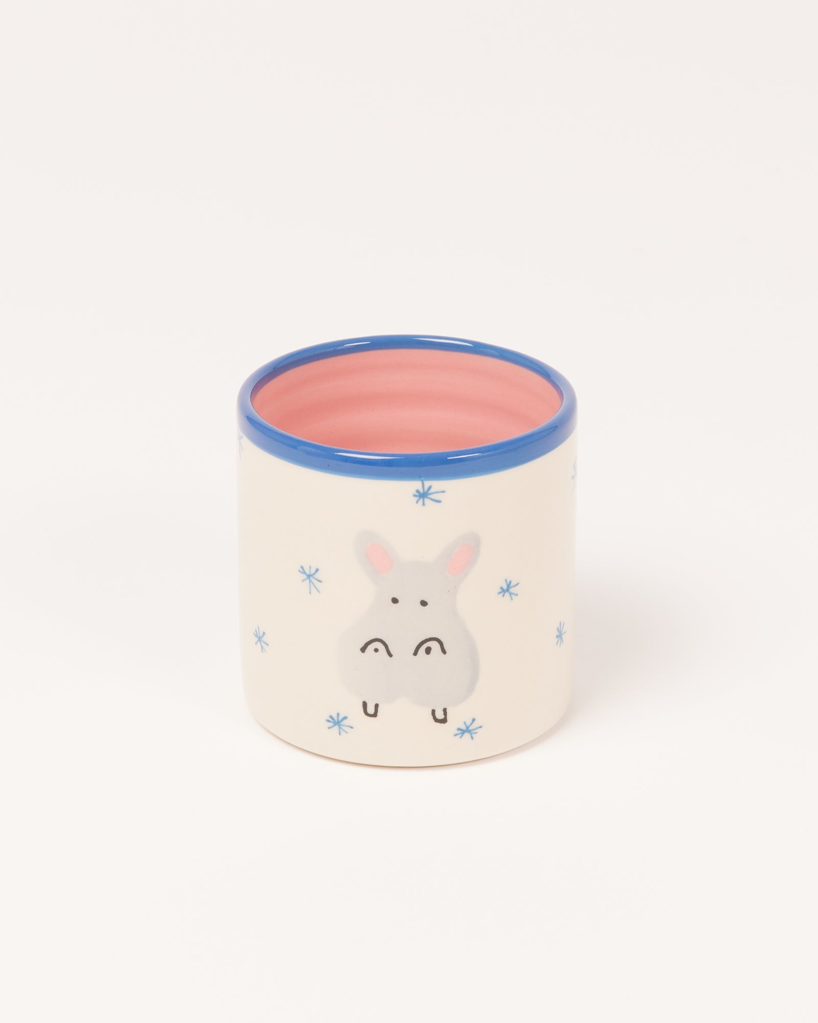 Keramikbecher mit blauem Rand und Hasenmotiv, dekoriert mit blauen Schneeflocken.