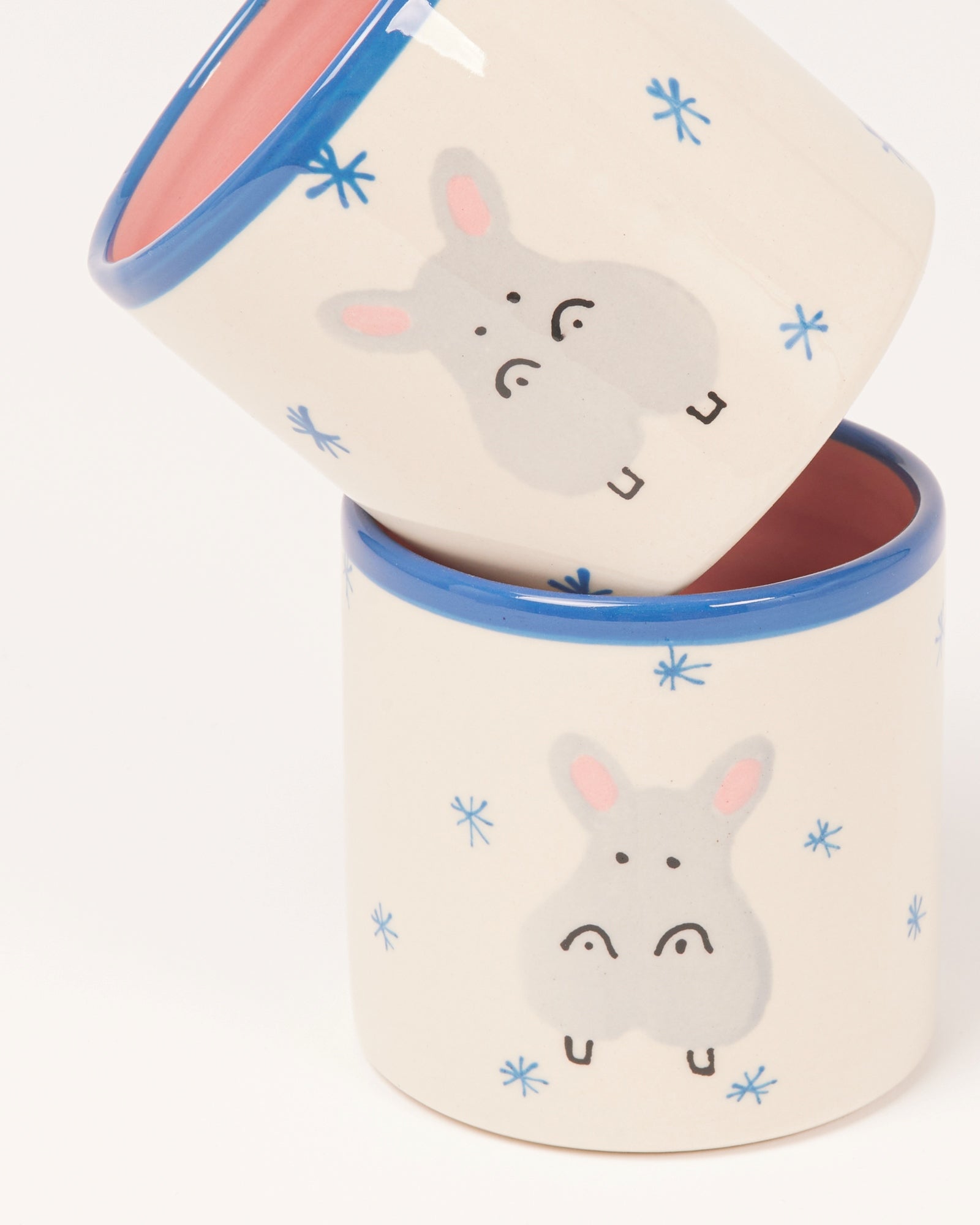 Zwei Stapelbecher mit Tiermotiven und blauen Rändern, mit Schneeflockenmuster verziert.