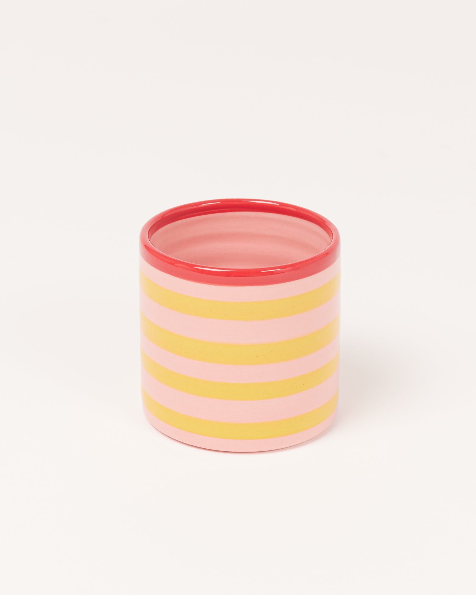 Ein Becher mit horizontalen rosa und gelben Streifen sowie einem roten Rand.