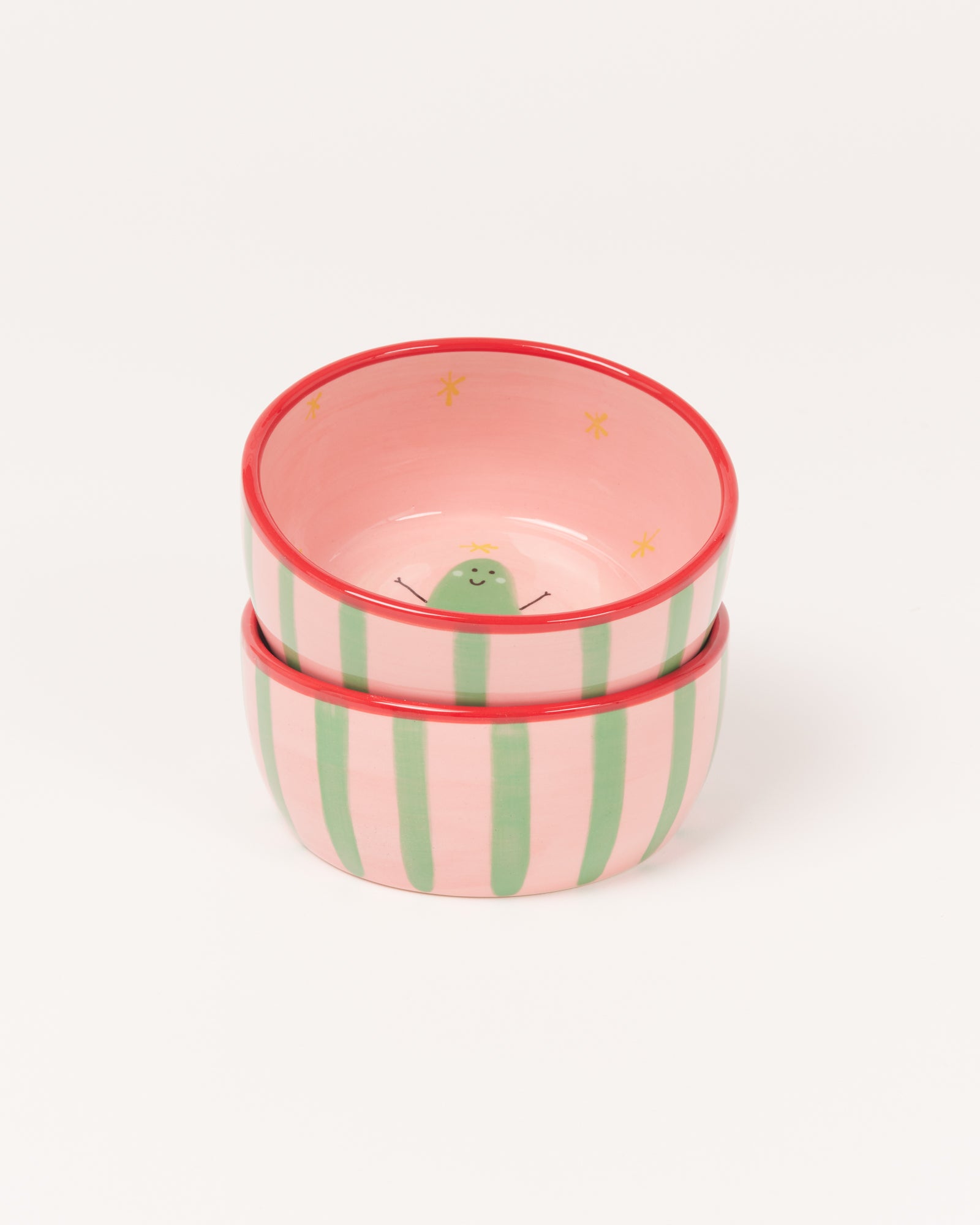Zwei gestapelte Schalen mit grün gestreiftem Muster und lachendem Kaktus-Design innen auf weißem Hintergrund.
