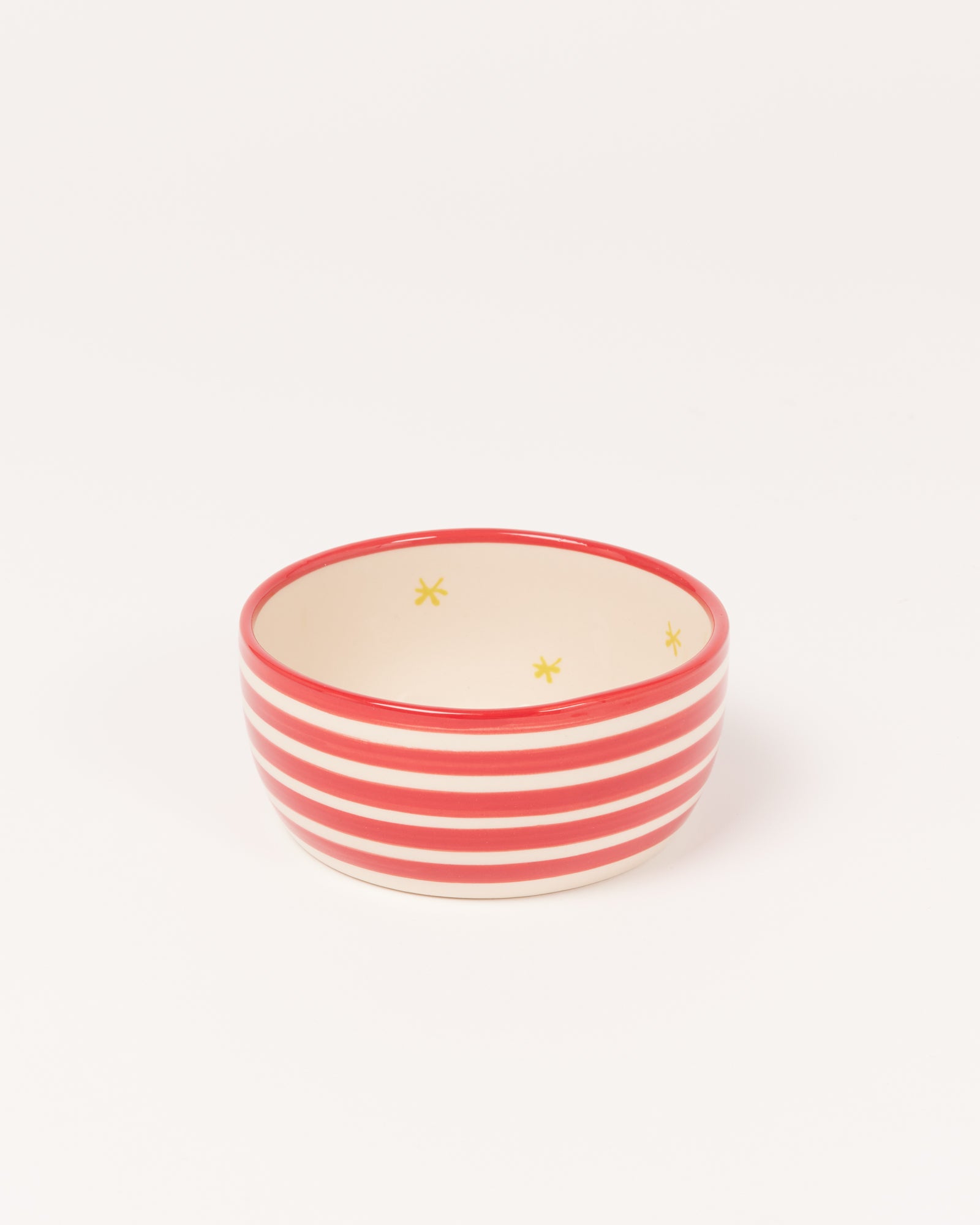 Kleine, rot-weiß gestreifte Schale mit gelben Sternen im Inneren auf weißem Hintergrund.