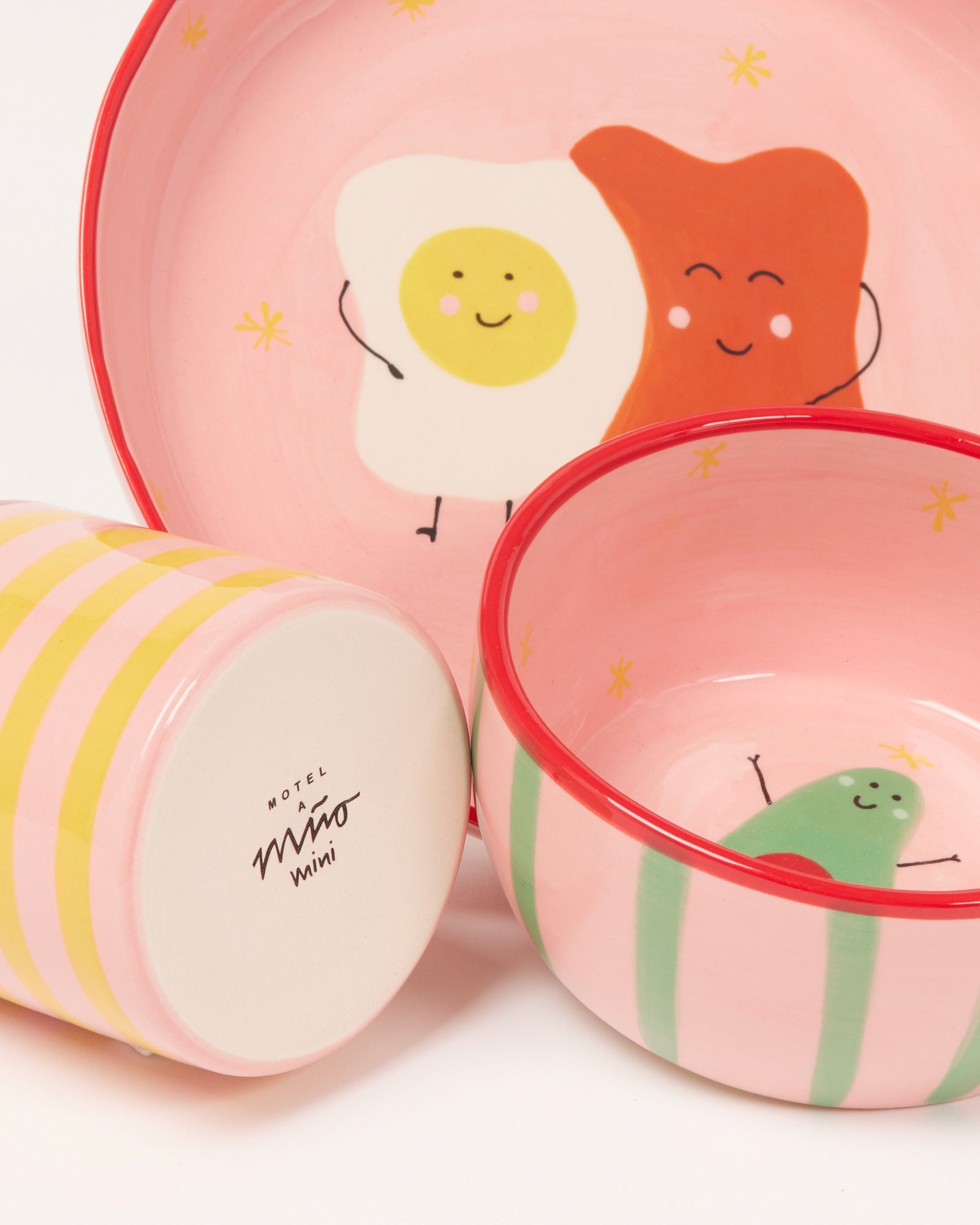 Pinkes Geschirrset mit fröhlichen Gesichtsmotiven: Spiegelei, Brot und Avocado.