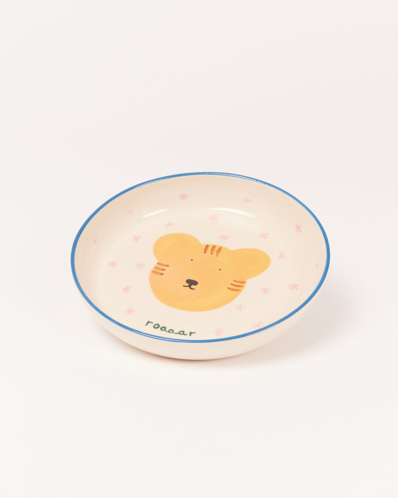 Weiße Schale mit blauem Rand und einem gelben Bärenmotiv in der Mitte, umgeben von rosa Sternen.