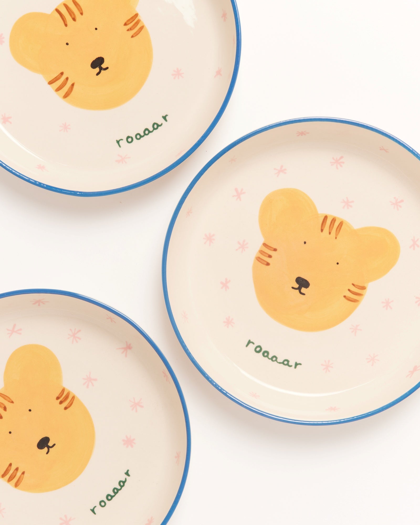 Drei Teller mit blauem Rand und Tigerzeichnung, das Wort "roaaar" ist auf jedem Teller geschrieben.