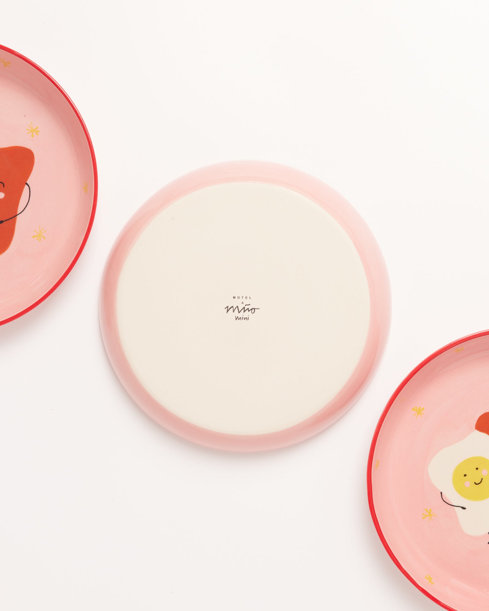 Drei bunte Teller auf einem weißen Hintergrund, zwei mit lachenden Gesichtern, der mittlere Teller ist umgedreht.