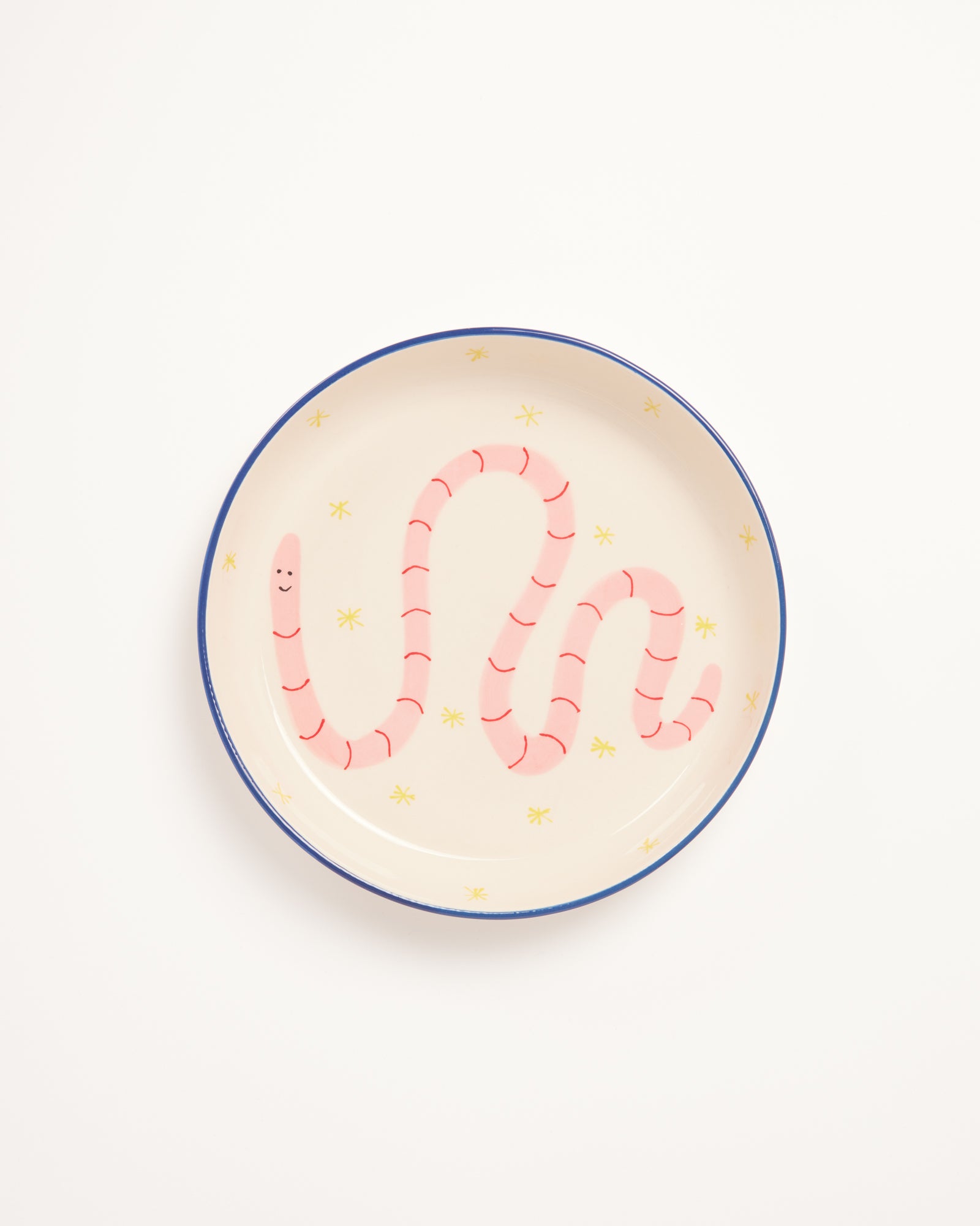 Ein Teller mit einem lächelnden rosa Wurm und gelben Sternen auf hellem Hintergrund.