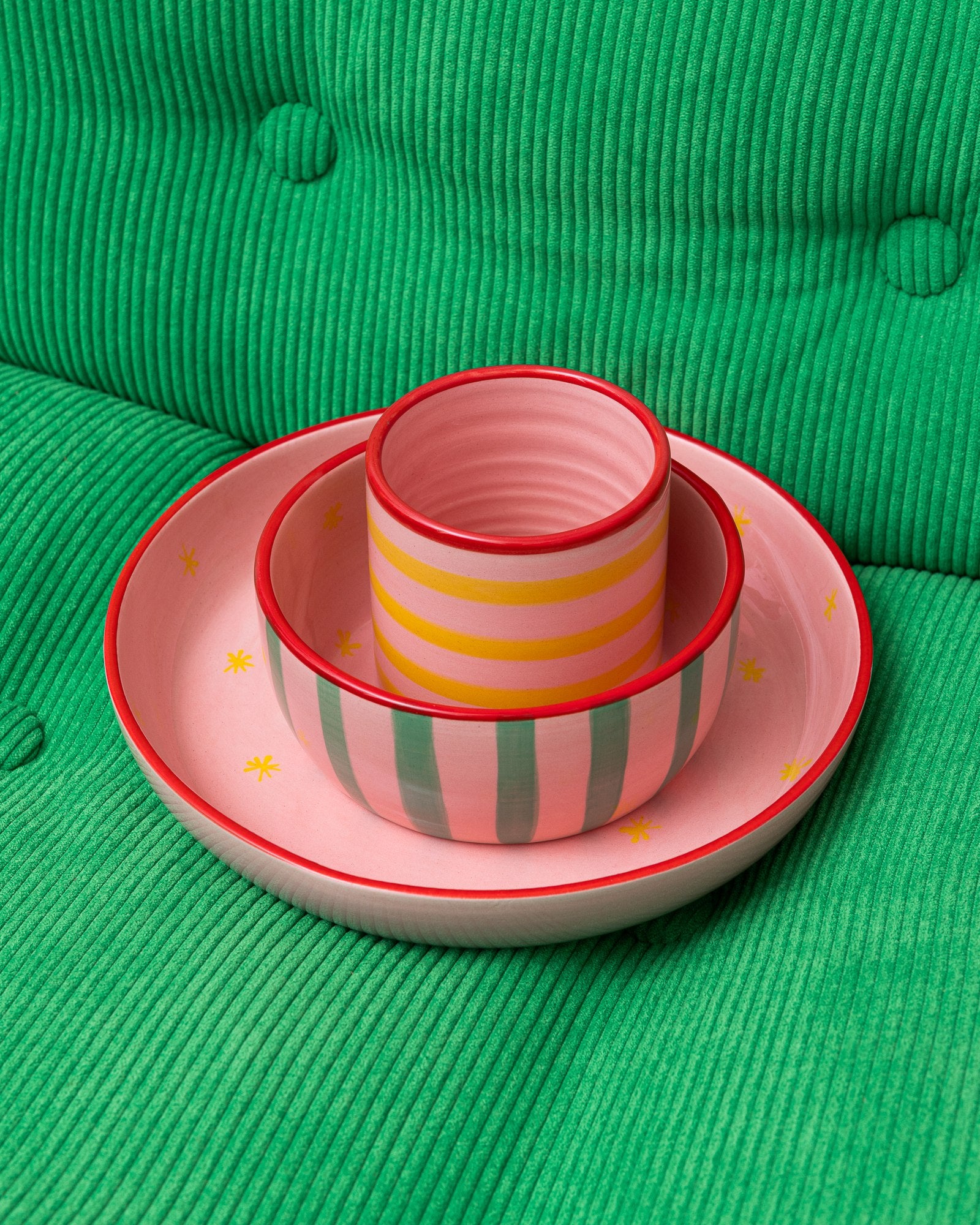 Drei bunte Keramikschalen in rosa und grün auf einem grünen, gesteppten Stoffhintergrund.