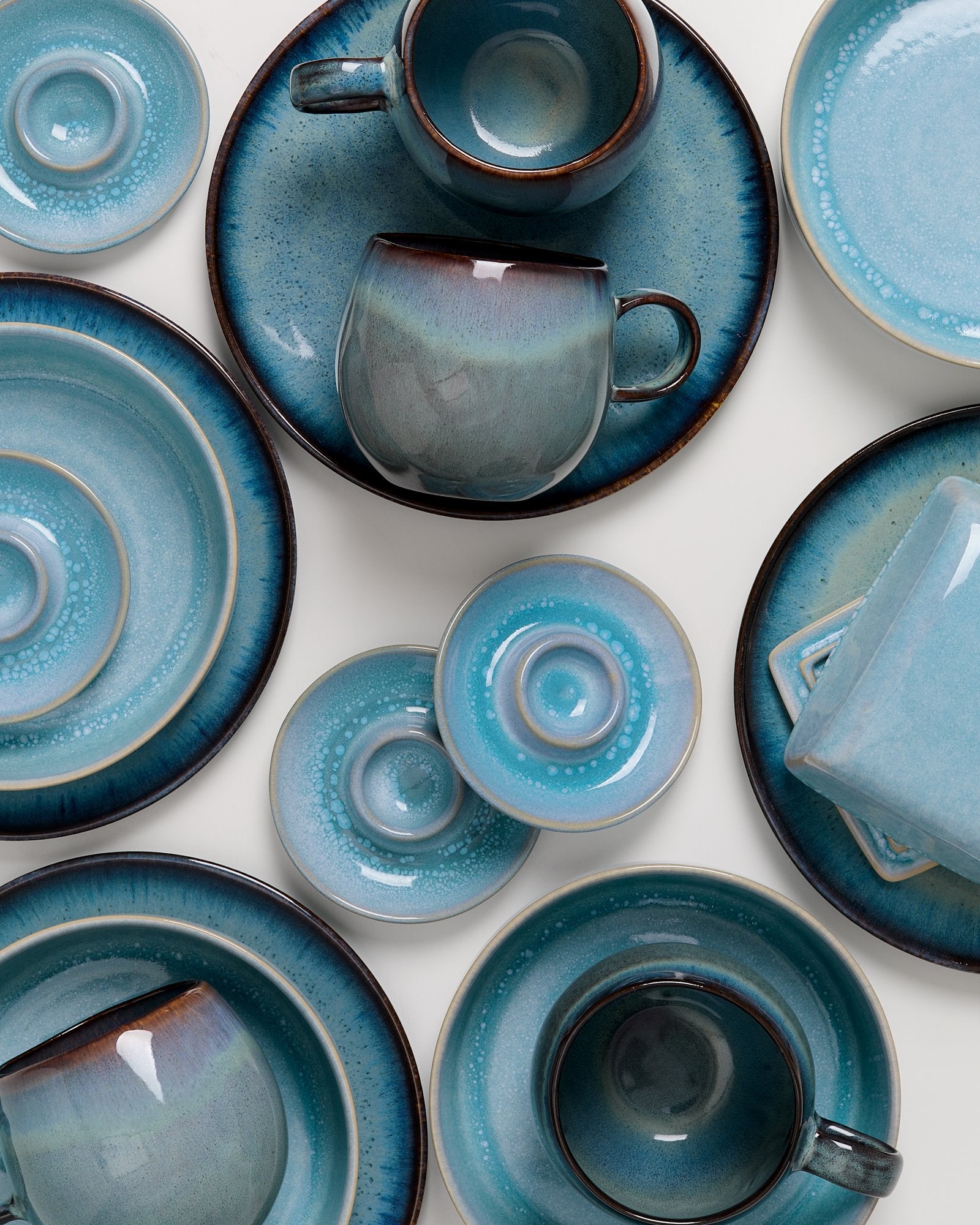 Verschiedene blaue Keramikgeschirrteile, darunter Tassen, Teller und Untertassen, sind auf weißem Hintergrund angeordnet.