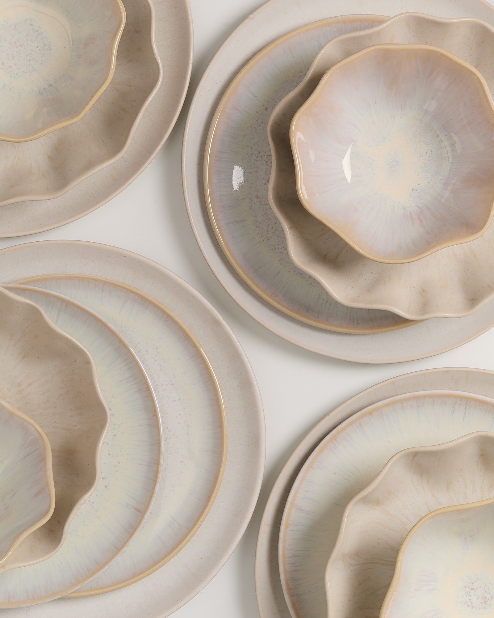 Keramikgeschirr in Pastellfarben, bestehend aus Tellern und Schalen mit organisch geschwungenen Rändern.