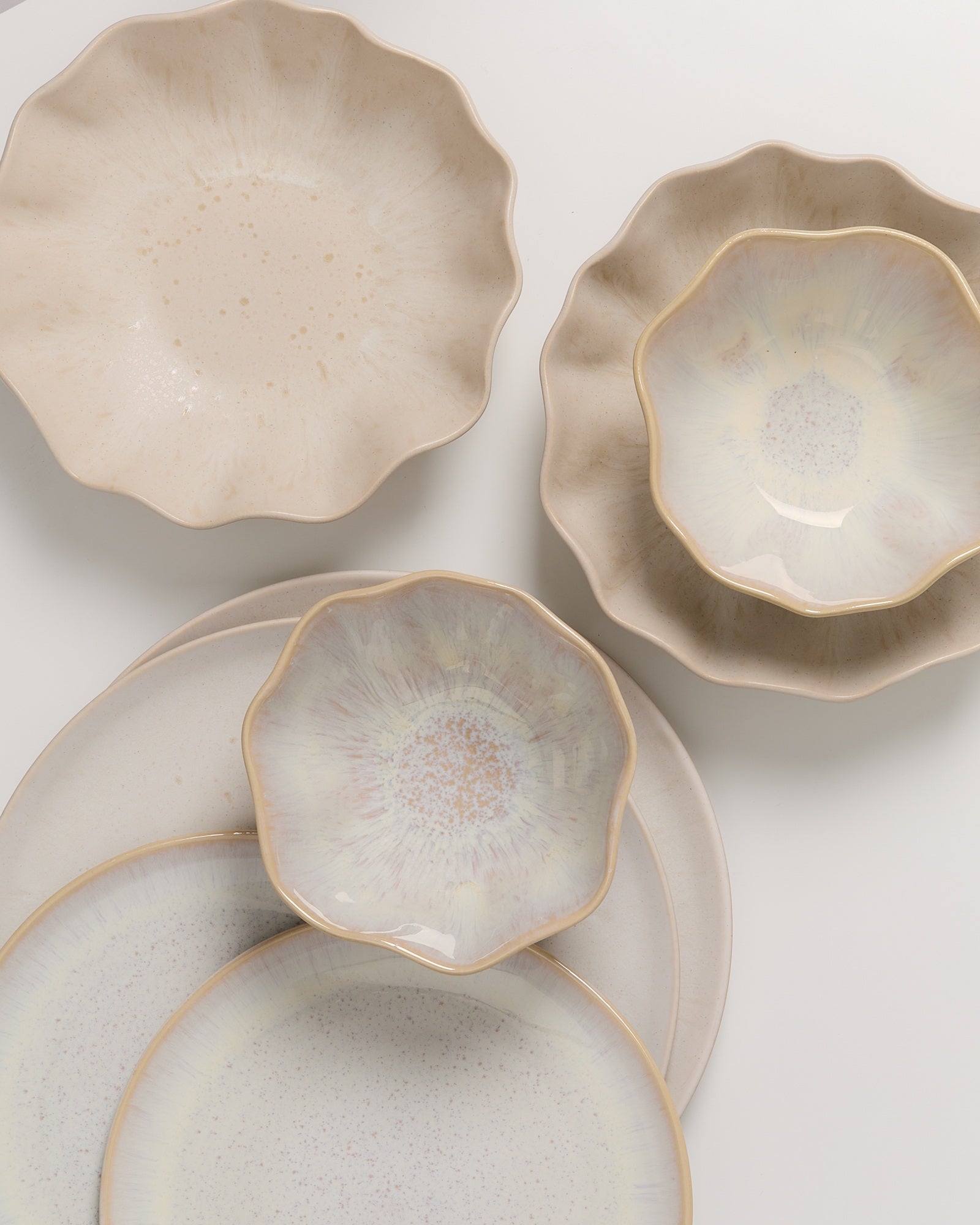 Beige und cremefarbene, blumenförmige Keramikteller und -schalen mit sanften Verläufen und zarten Mustern.