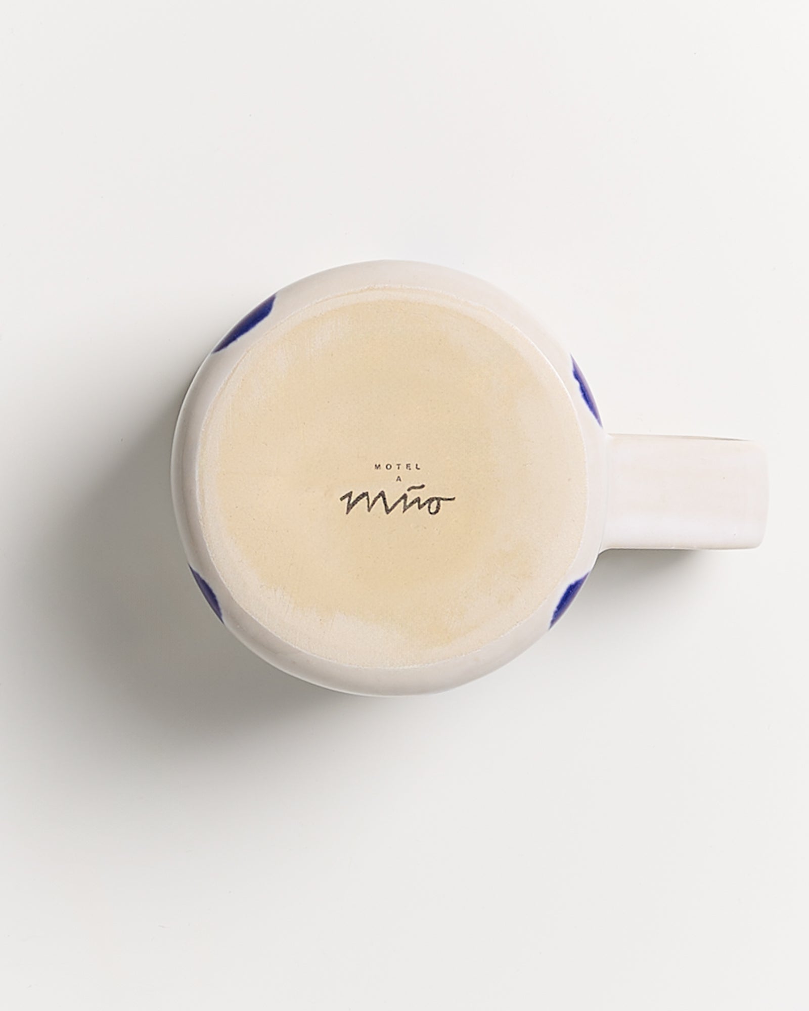 Unterseite einer Tasse mit der Aufschrift "Motel a Miio" auf hellem Hintergrund.
