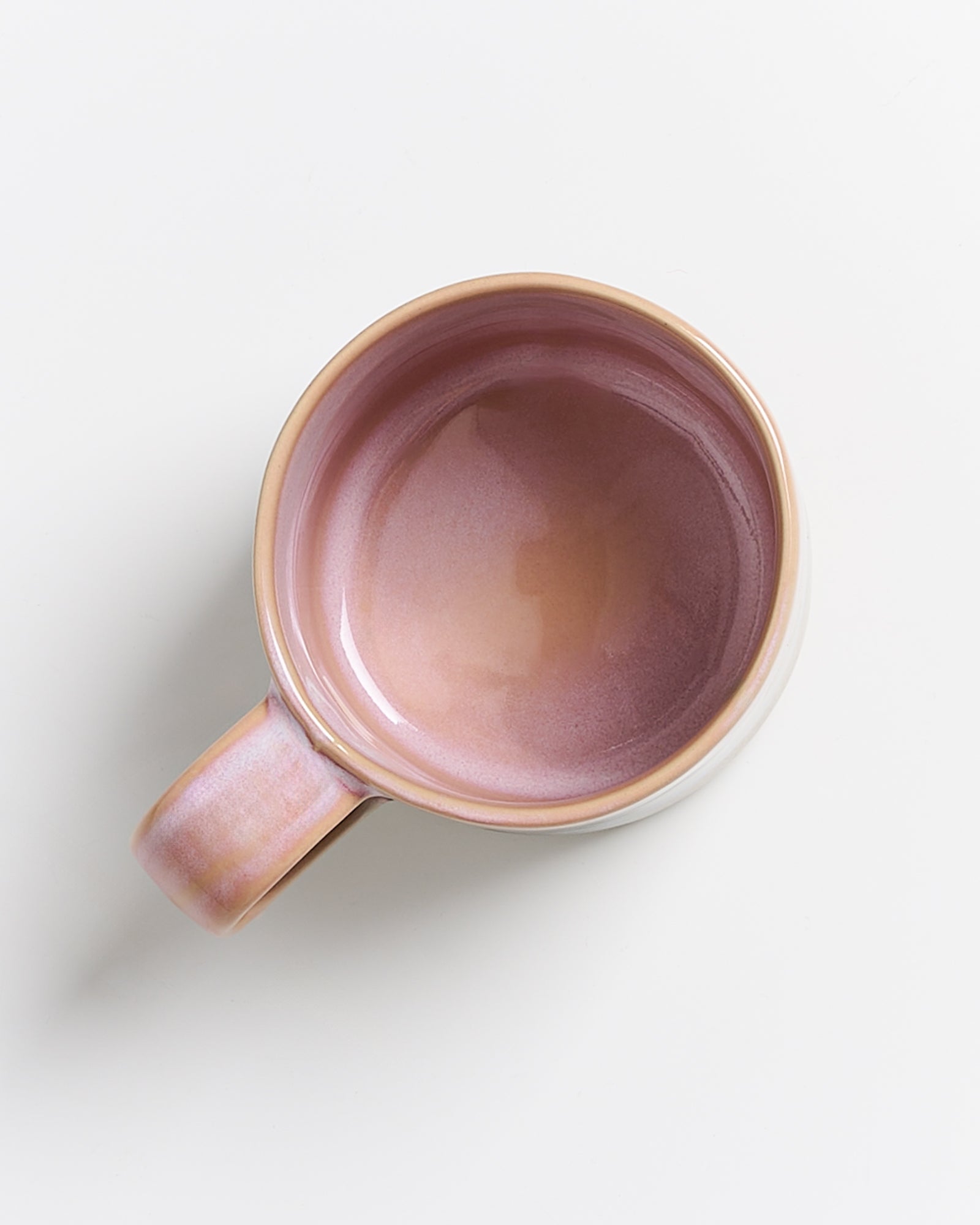 Keramiktasse mit rosa Innenfläche, von oben fotografiert auf weißem Hintergrund.