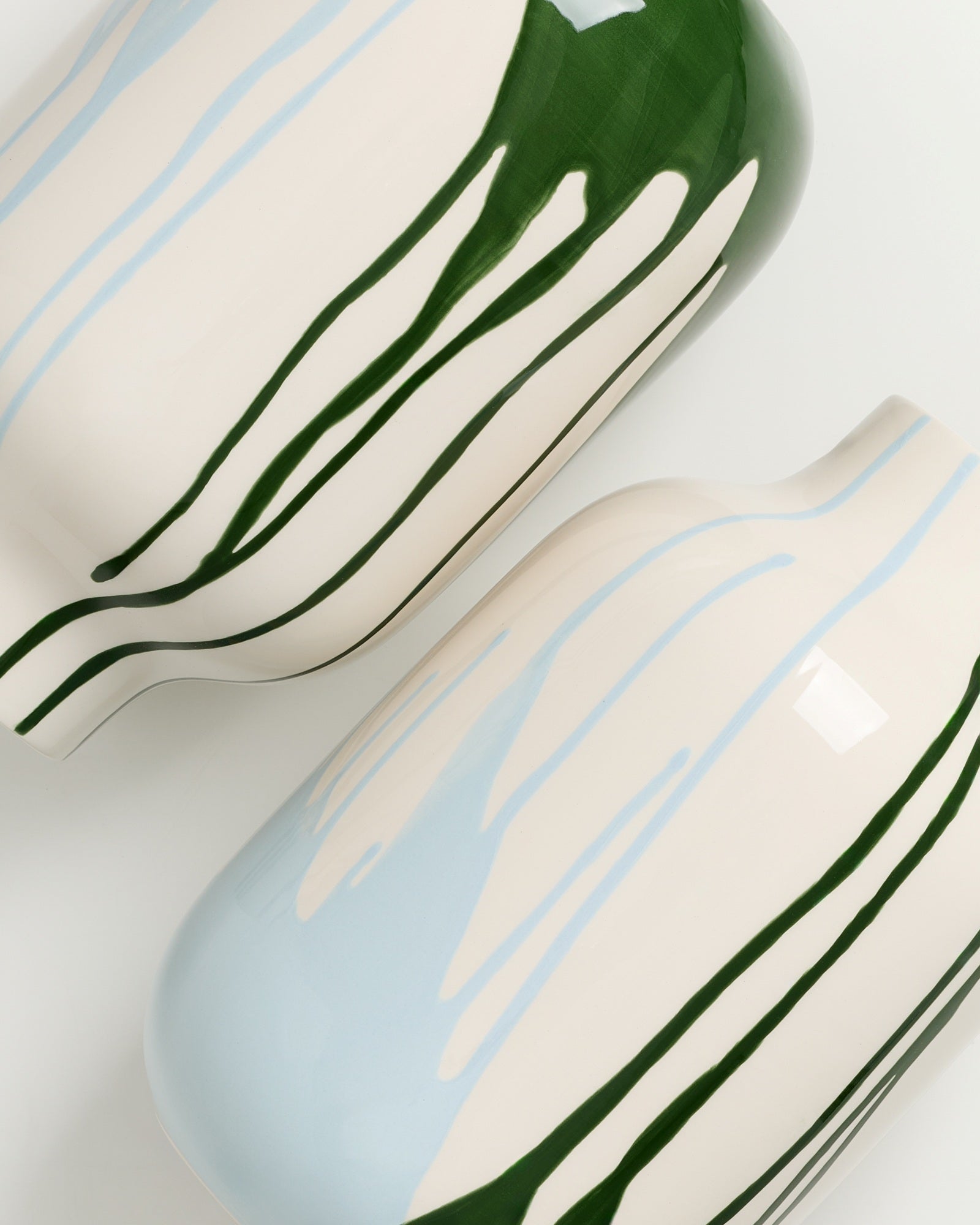 Zwei Vasen mit fließendem blauem und grünem Muster auf hellbeigem Hintergrund.