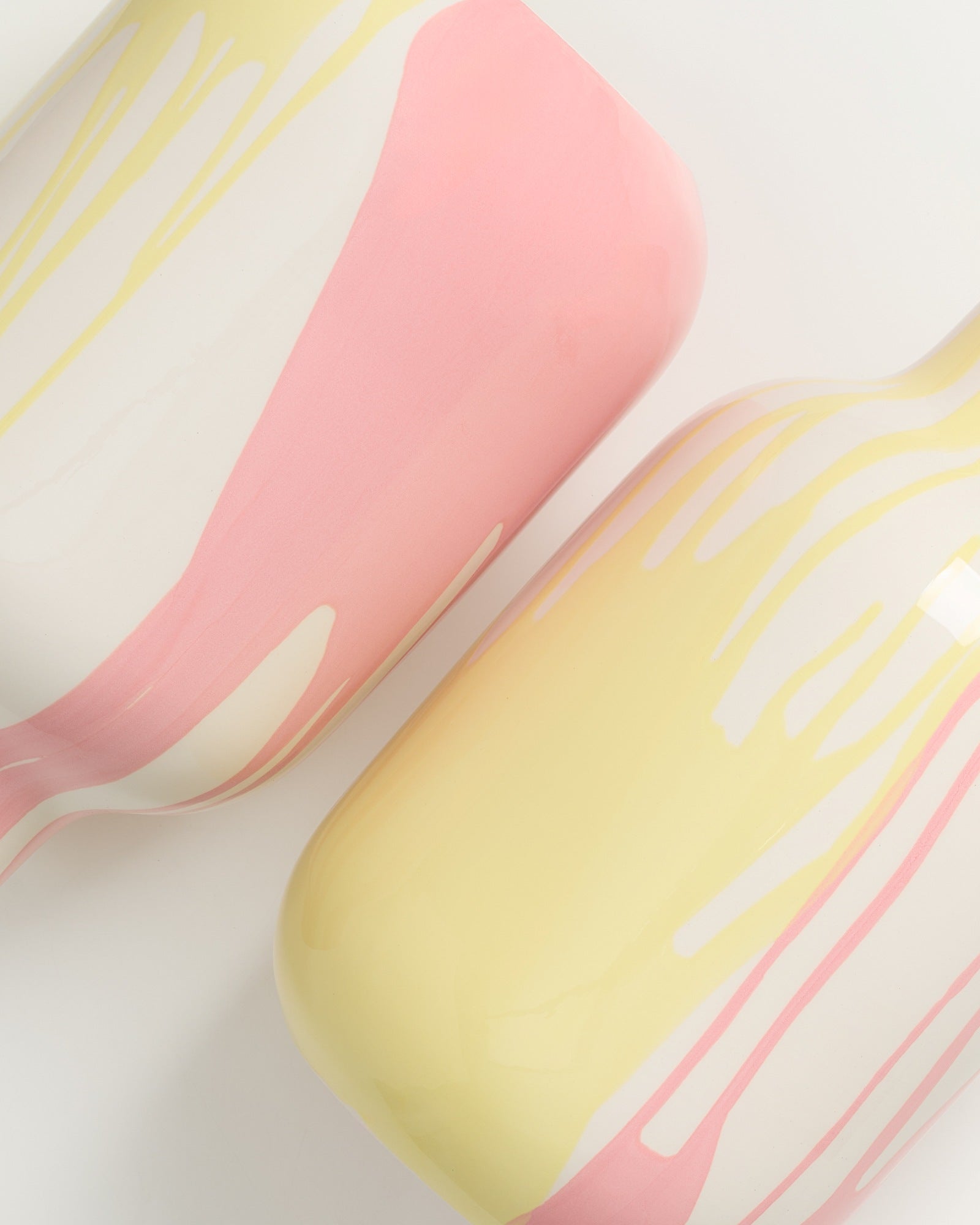 Zwei Vasen mit fließendem Rosa und Gelb auf weißem Hintergrund, in einem modernen, minimalistischen Stil.