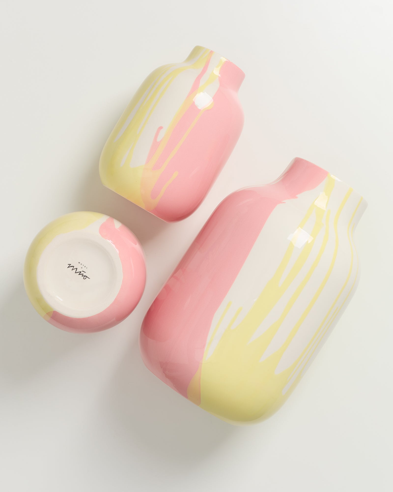 Drei farbenfrohe Vasen in Pink, Gelb und Weiß liegen auf einem weißen Hintergrund.