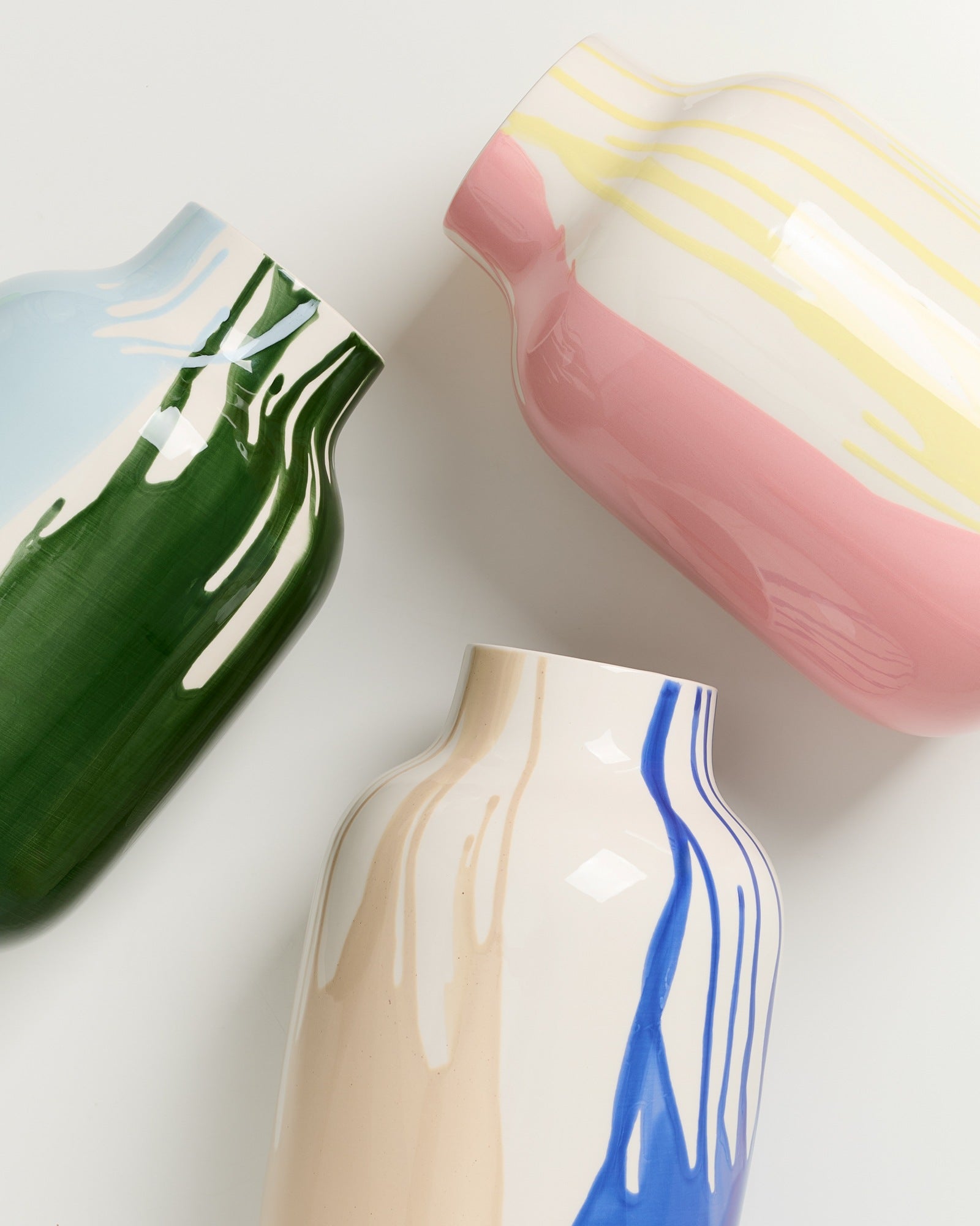 Drei bunte Keramikvasen mit abstrakten Mustern in Grün, Rosa und Blau auf weißem Hintergrund.